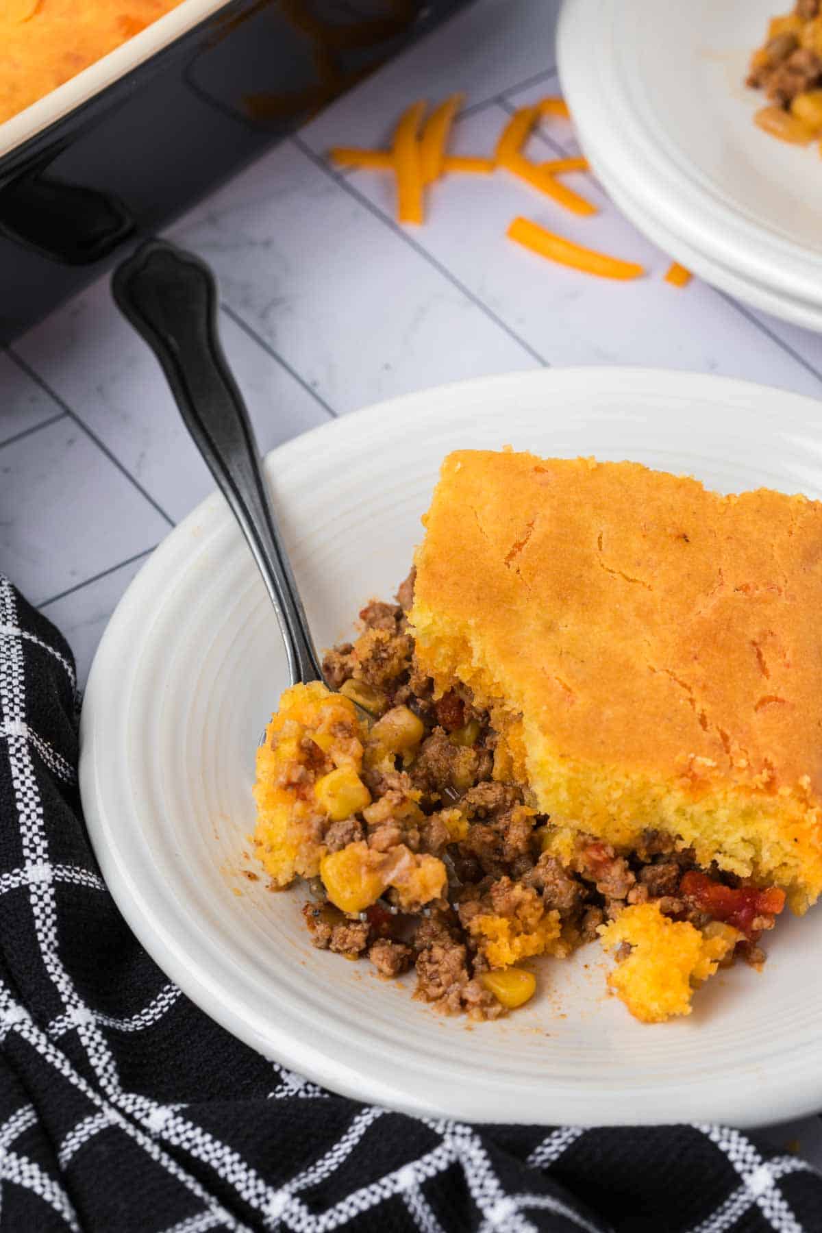 A serving of cornbread casserole on a plate with a spoon