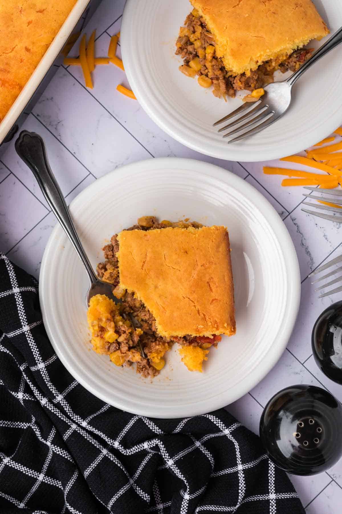 A serving of cornbread casserole on a plate with a fork