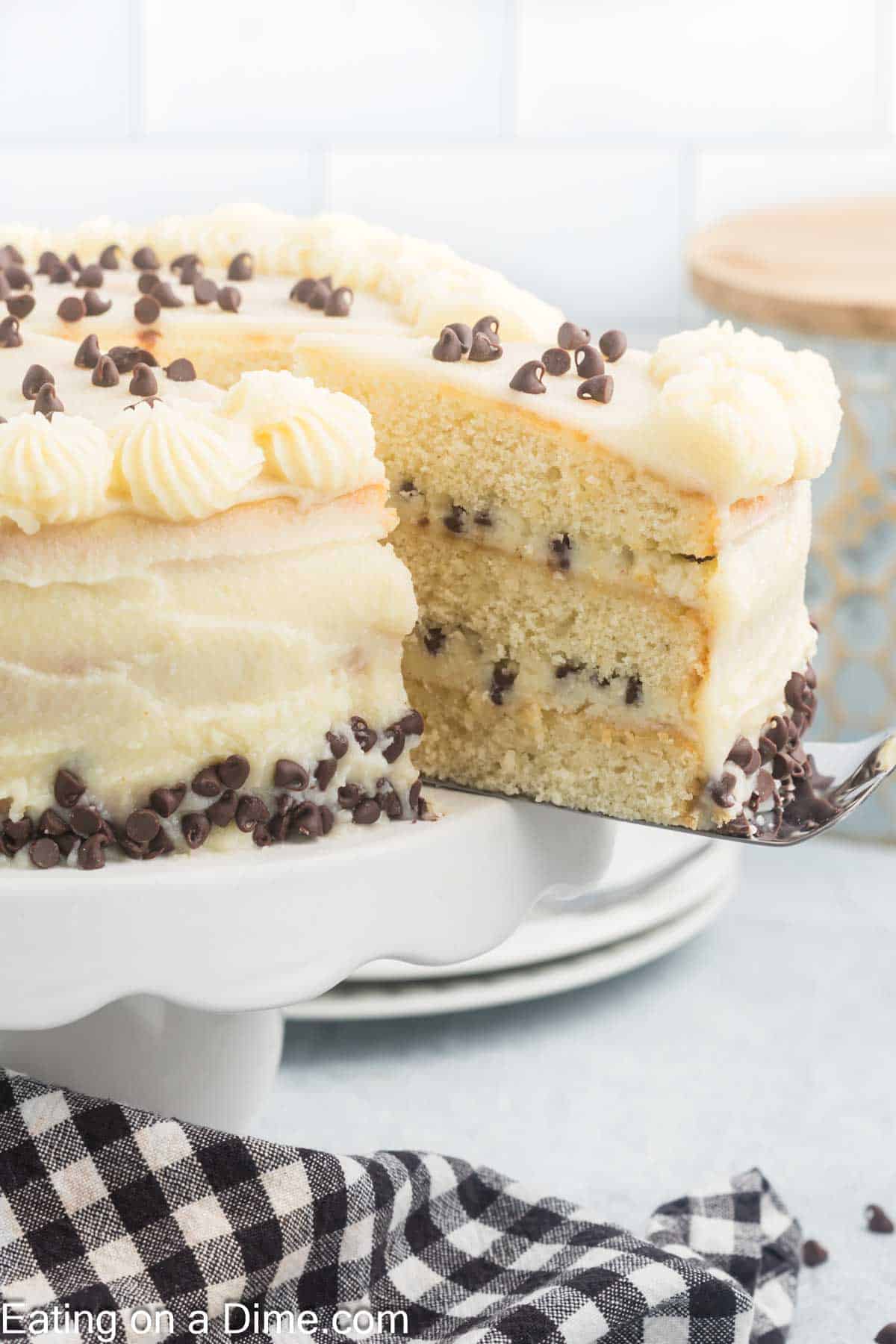 Cannoli Cake on a cake stand with a slice cut and on a spatula