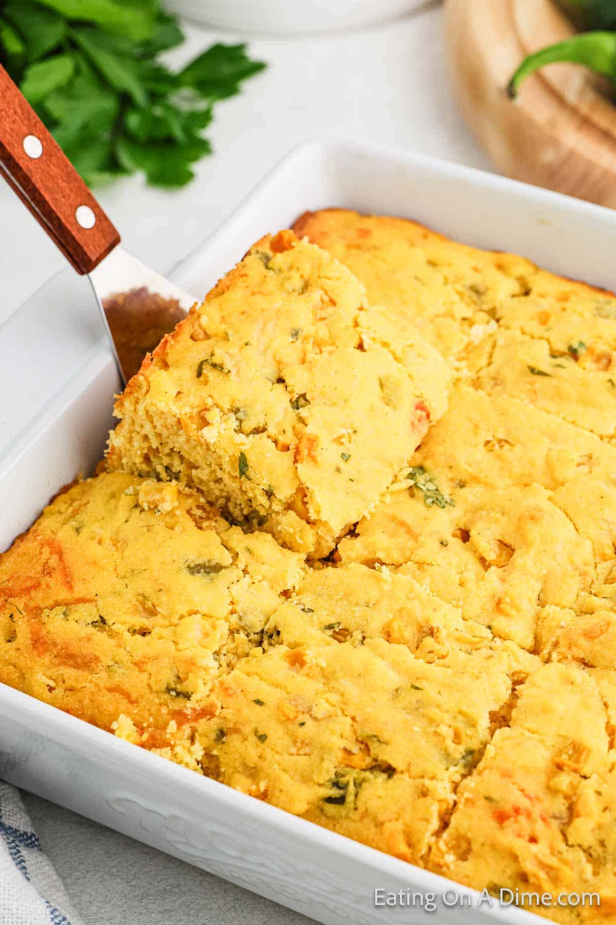 Mexican Cornbread in a baking dish cut into squares with a slice on a spatula