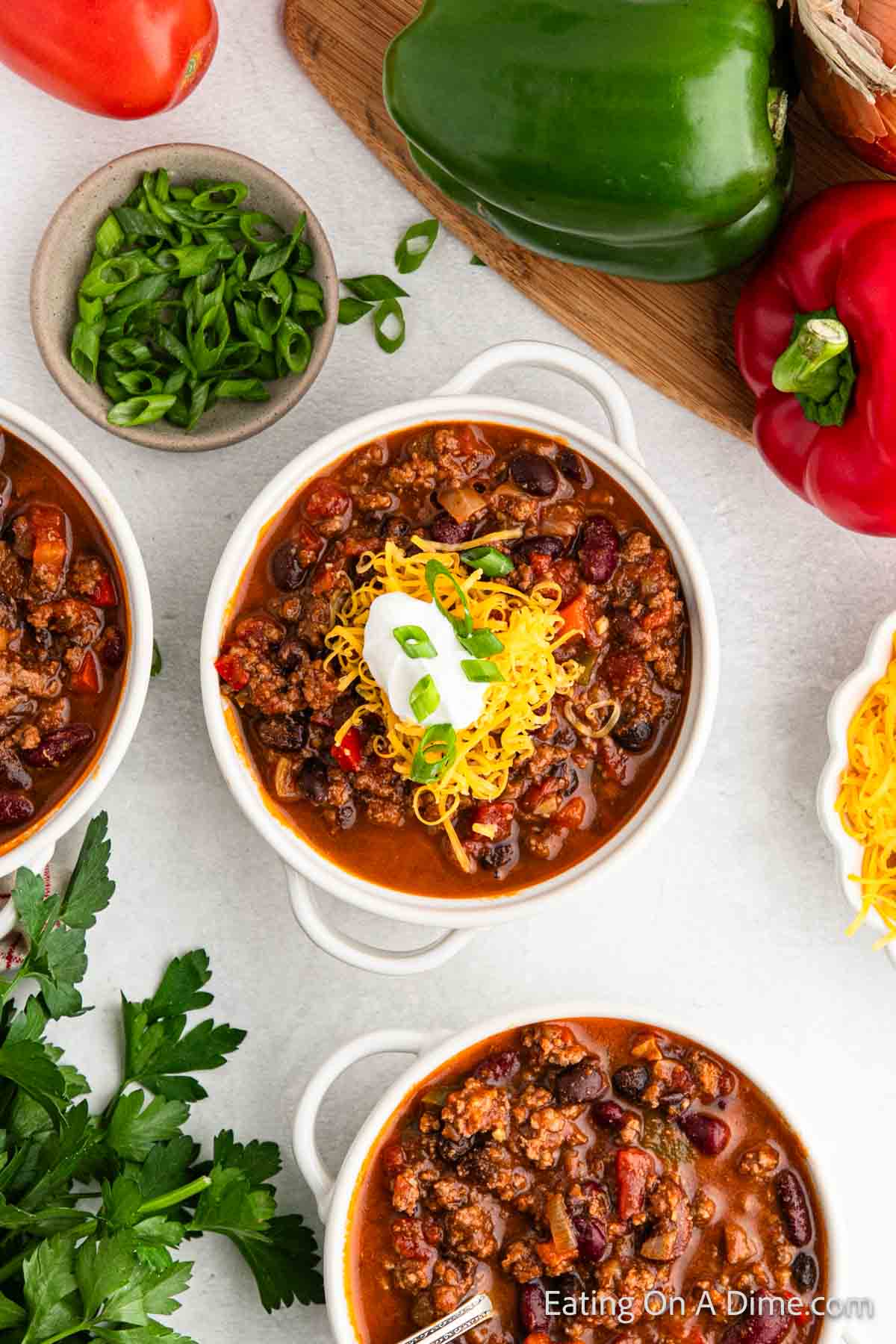 Venison chili in a bowl topped with shredded cheese, sour cream, and chopped green onions