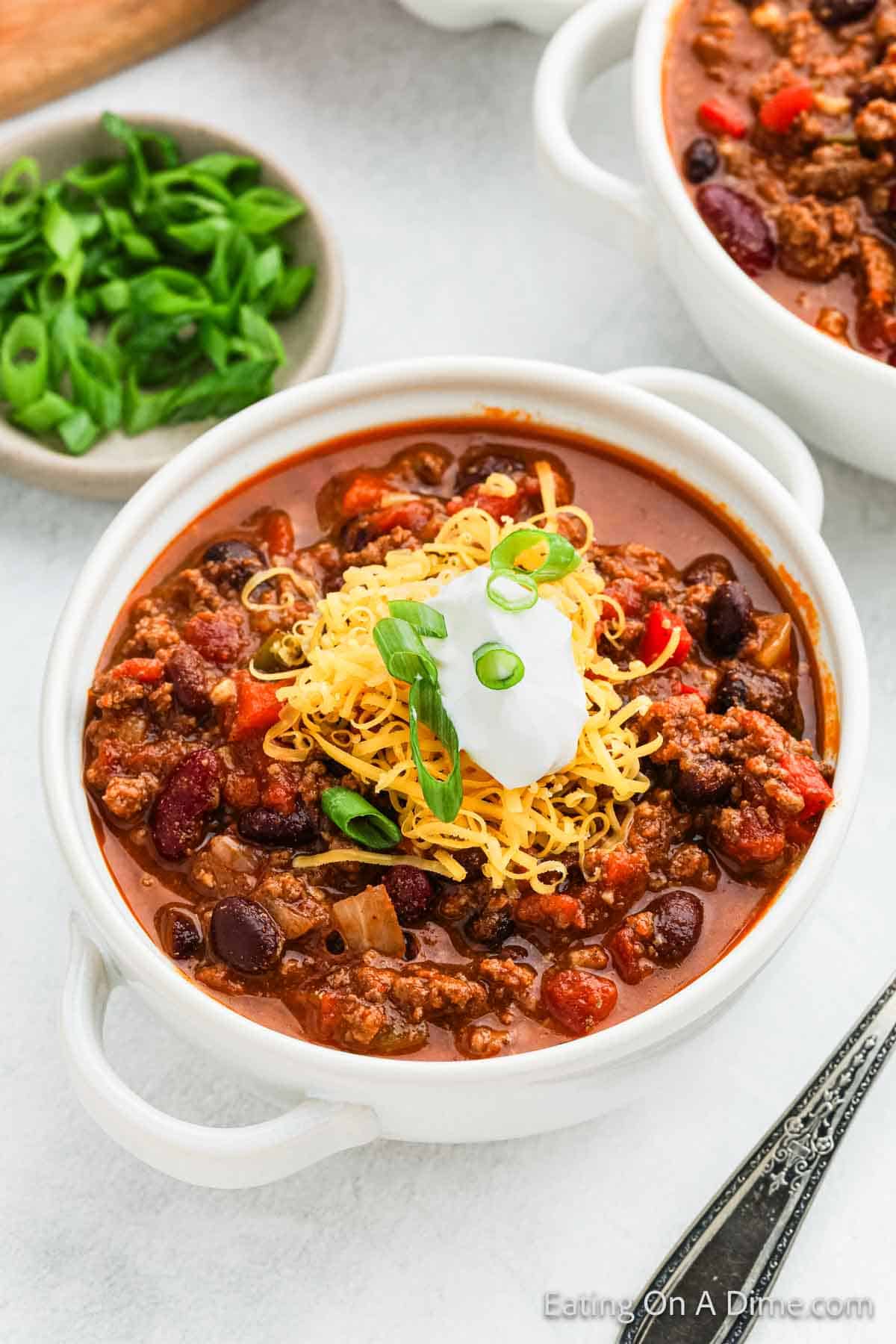 Venison chili in a bowl topped with shredded cheese, sour cream and chopped green onions