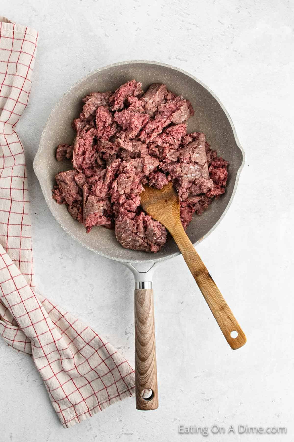 Cooking ground venison in a skillet with a wooden spoon