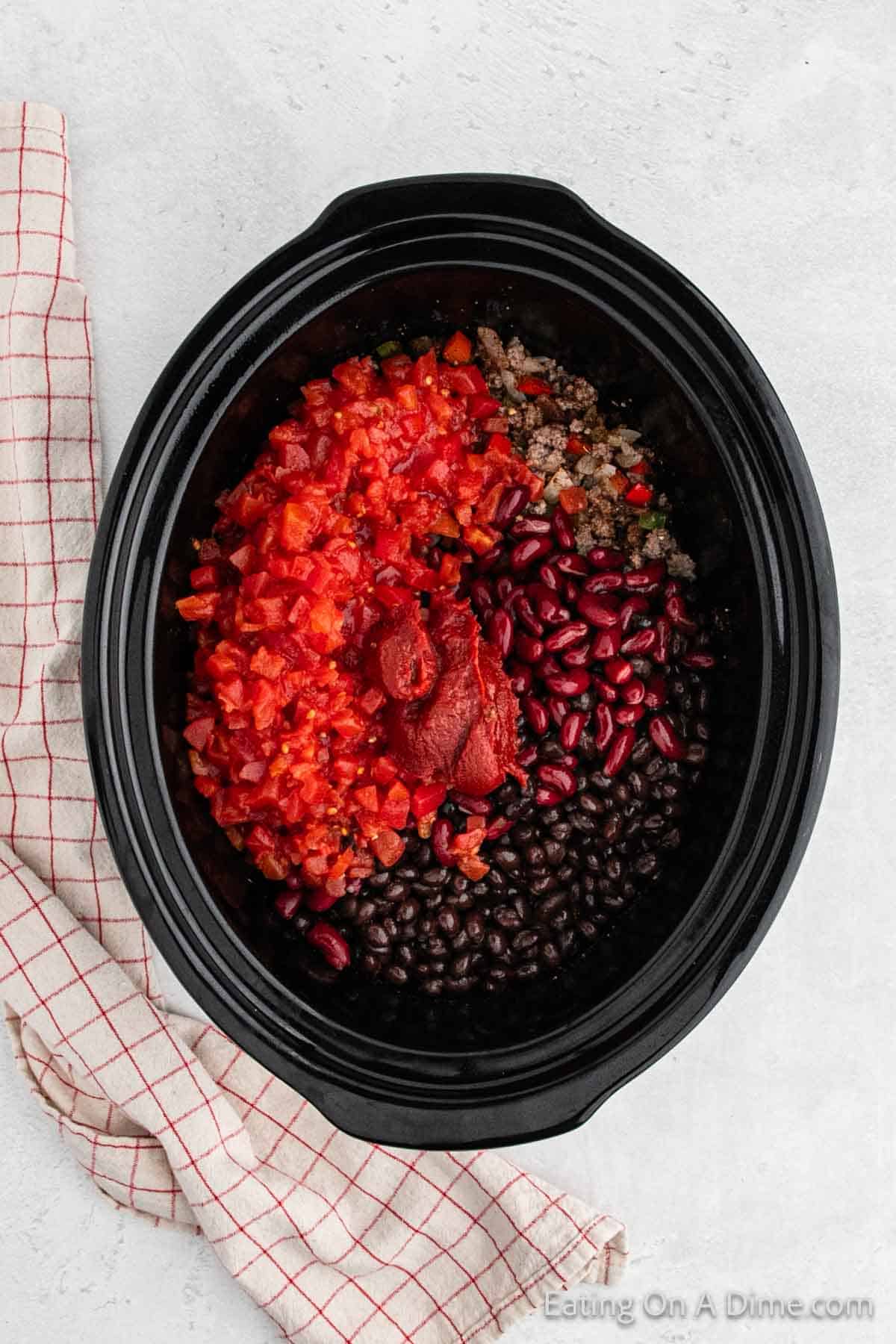 Adding the diced tomatoes, tomato paste, beans in the slow cooker