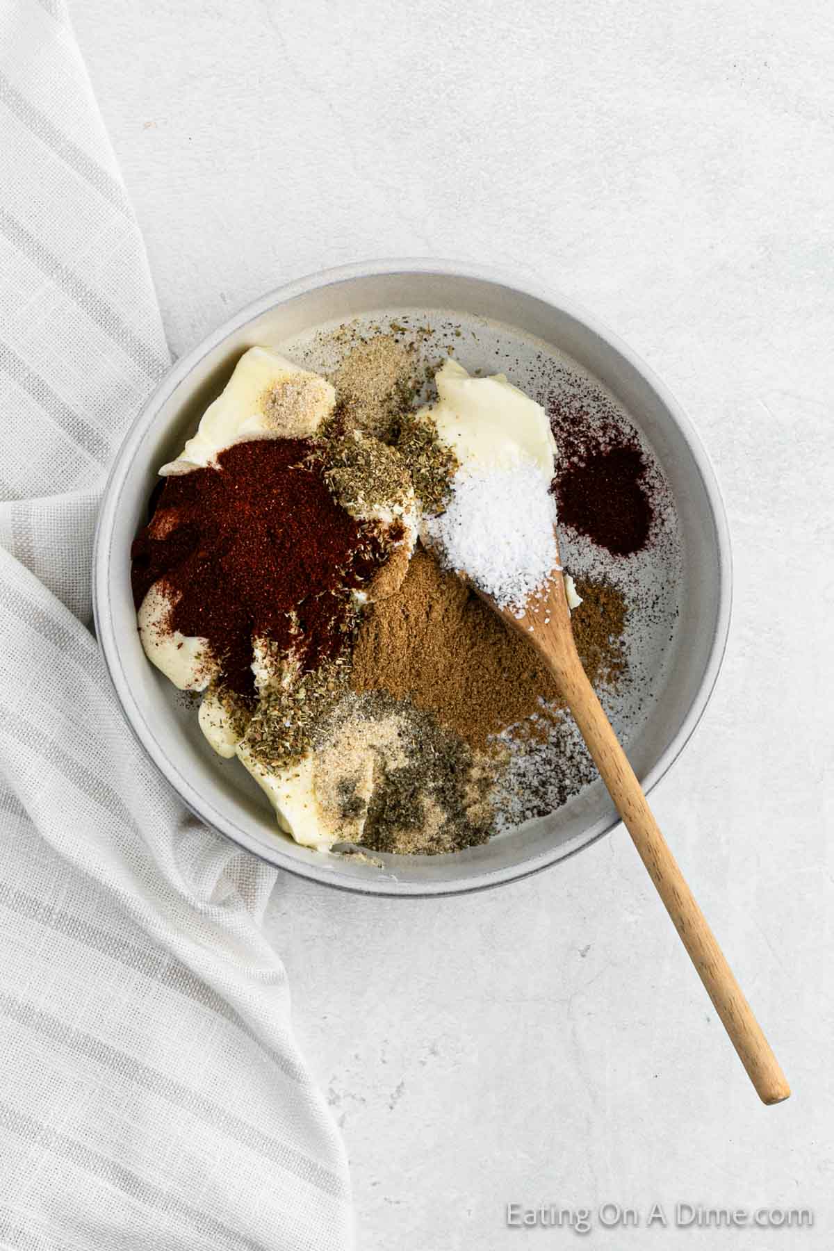 Combining softened butter with the spices in a bowl with a wooden spoon