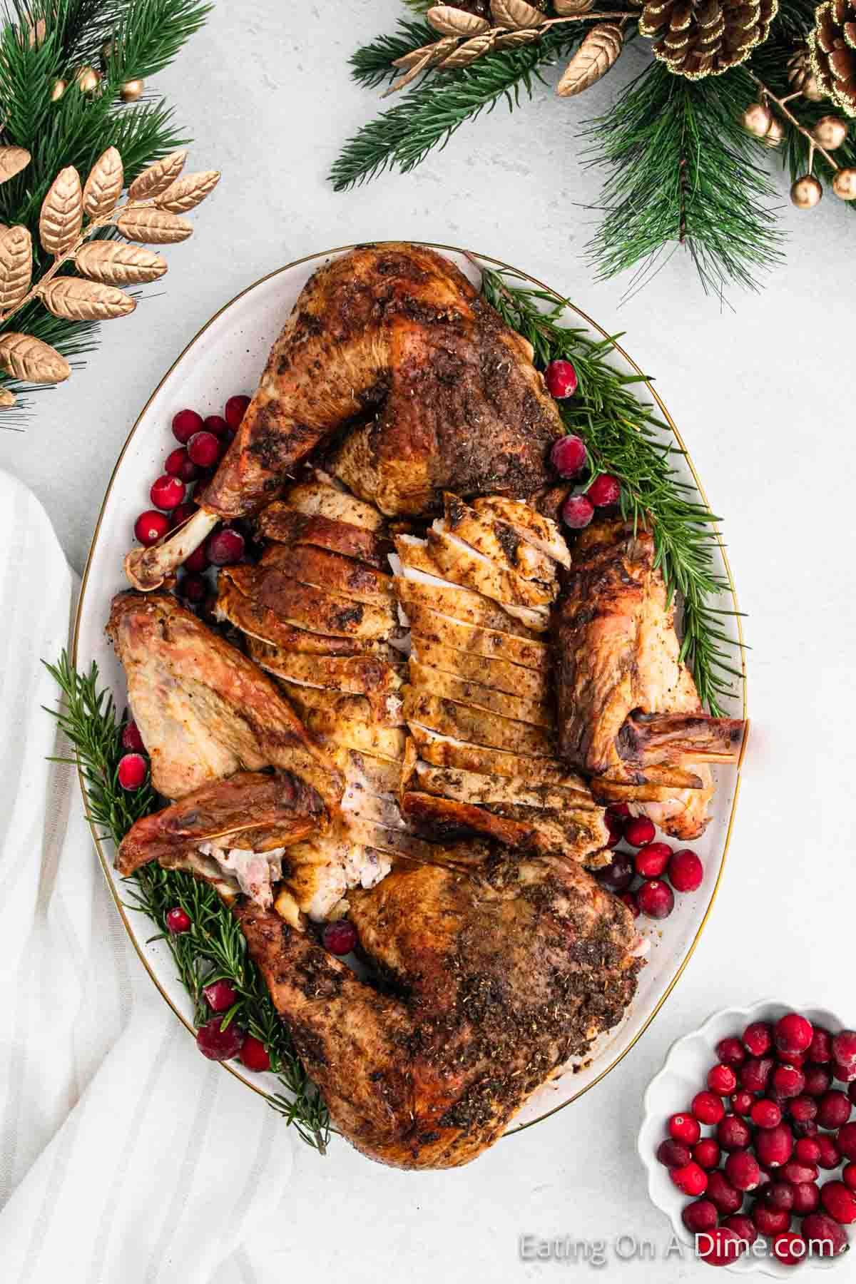 Golden Brown Turkey Sliced on a platter with evergreen and cranberries as decorations on the platter