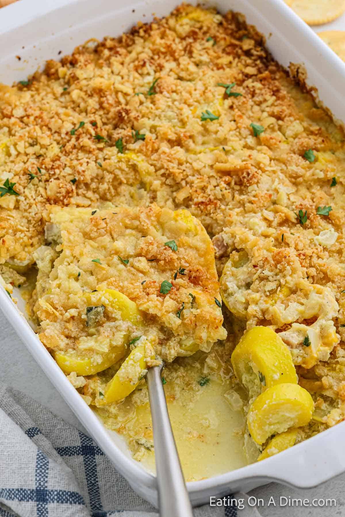 Baked Squash Casserole in a baking dish with a serving on a spatula