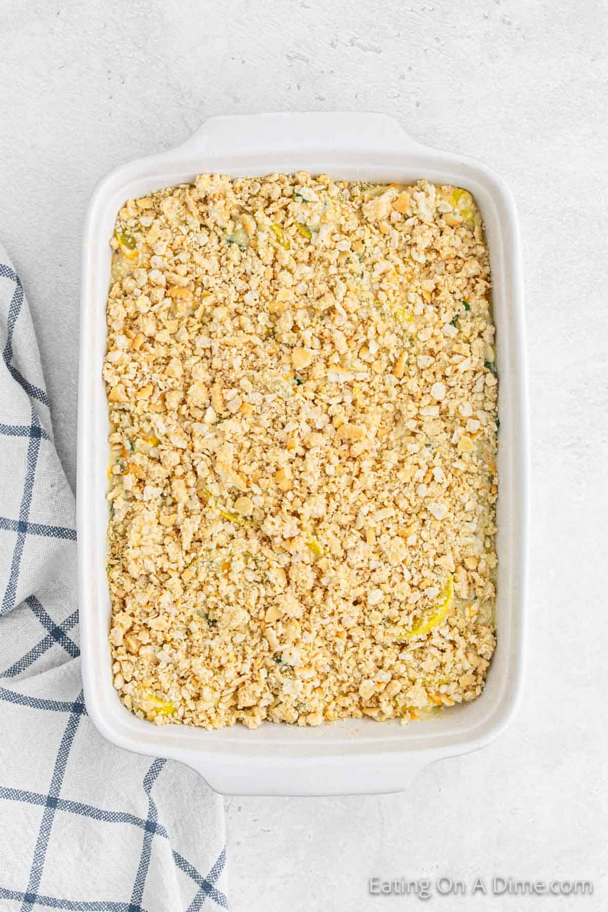 Adding the crushed crackers over the top of squash mixture in a baking dish