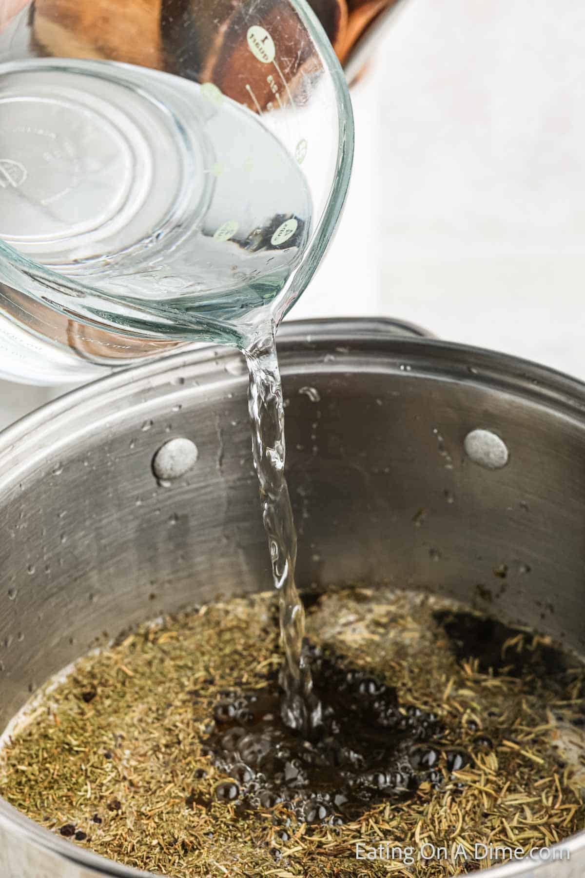 Pouring water in the large pot over the fresh spices