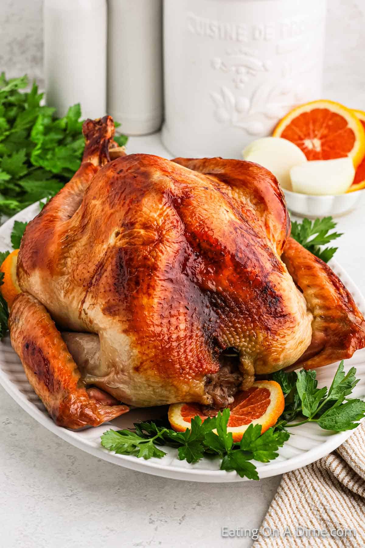 Golden Brown Whole Turkey on a large platter with fresh herbs and orange slices