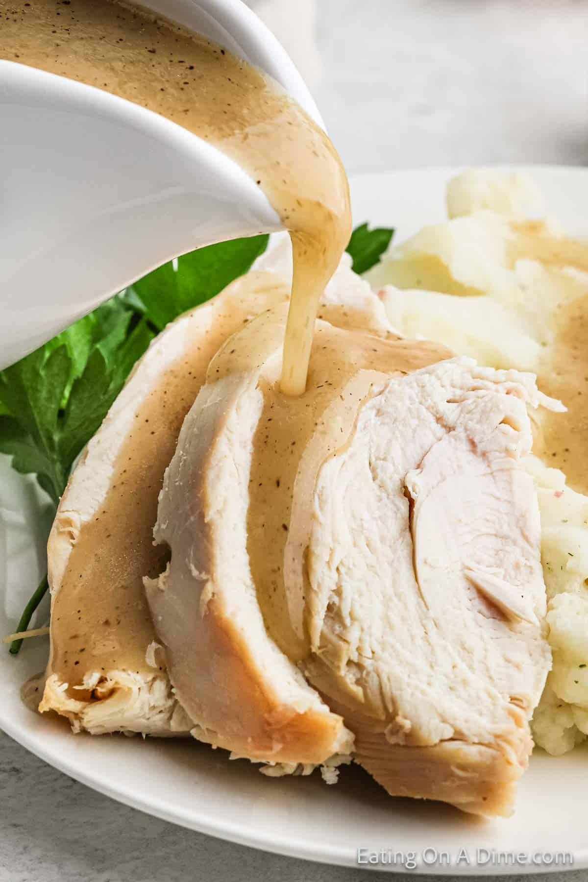 Pouring gravy over sliced turkey on a plate