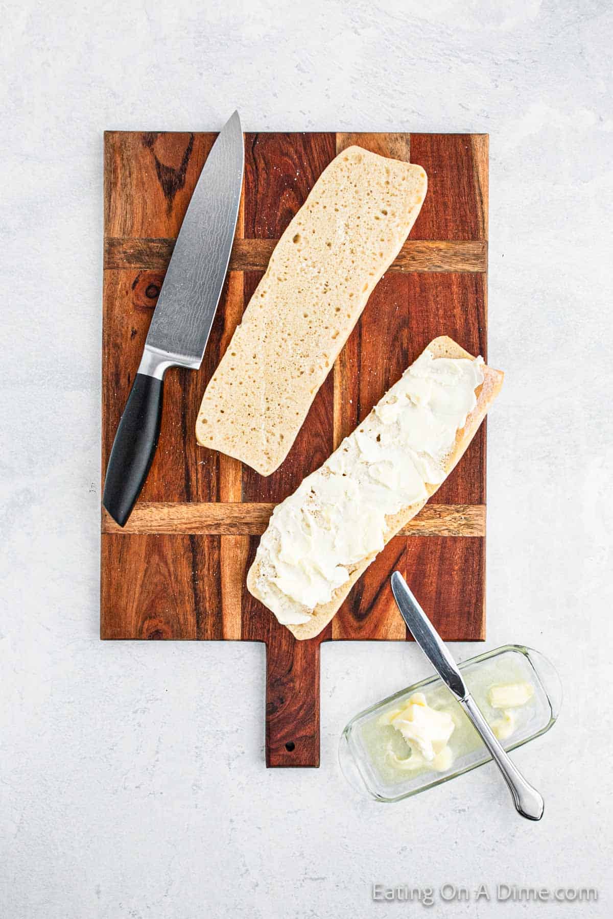 Slice Ciabatta Bread on cutting board with a knife with butter spread on one slice