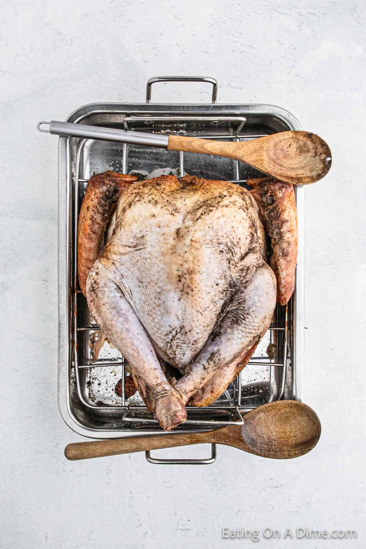 Roasted Whole Turkey on a roasting pan with two wooden spoons