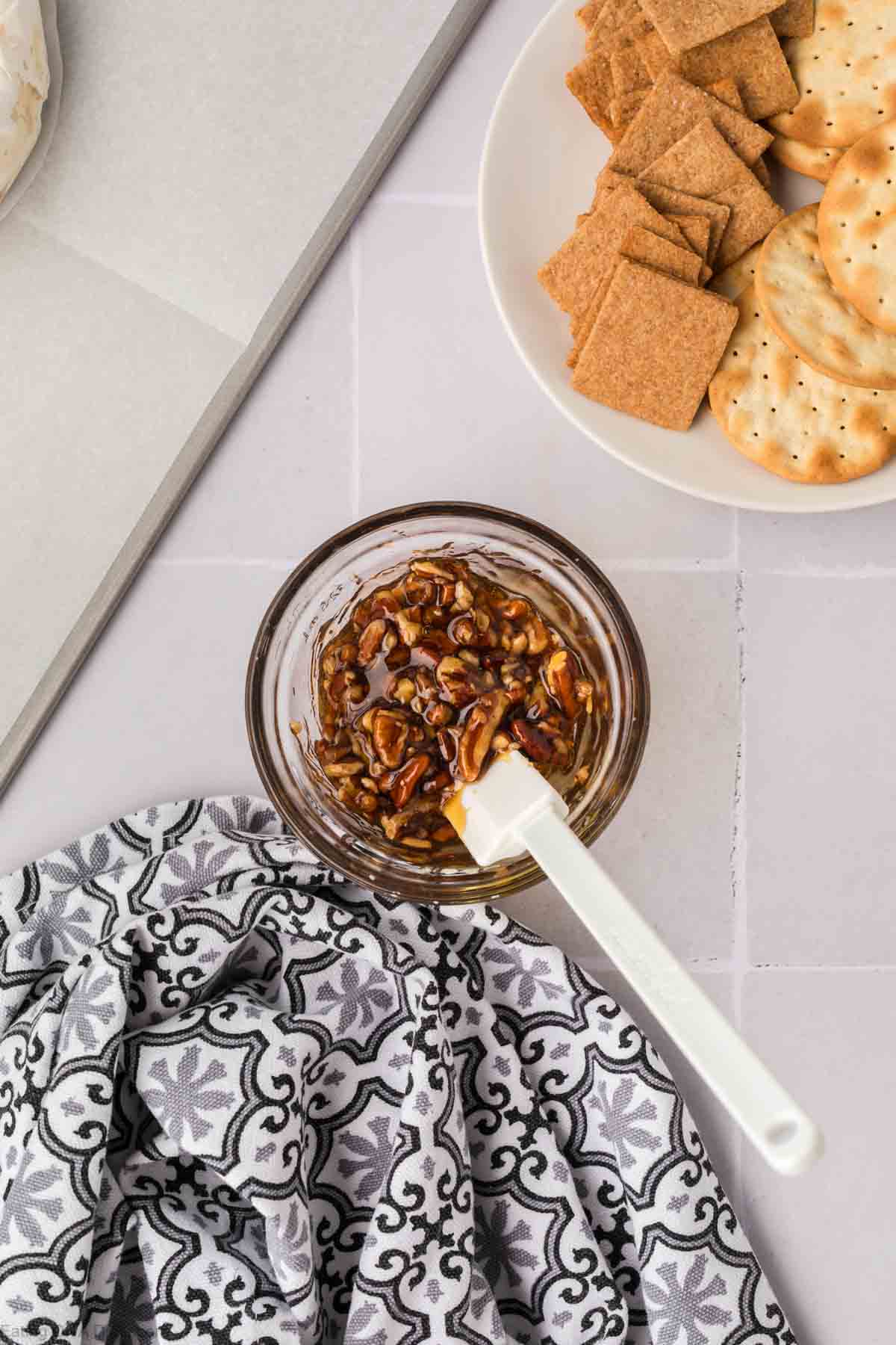 Mixing pecans with honey in a bowl with a spatula