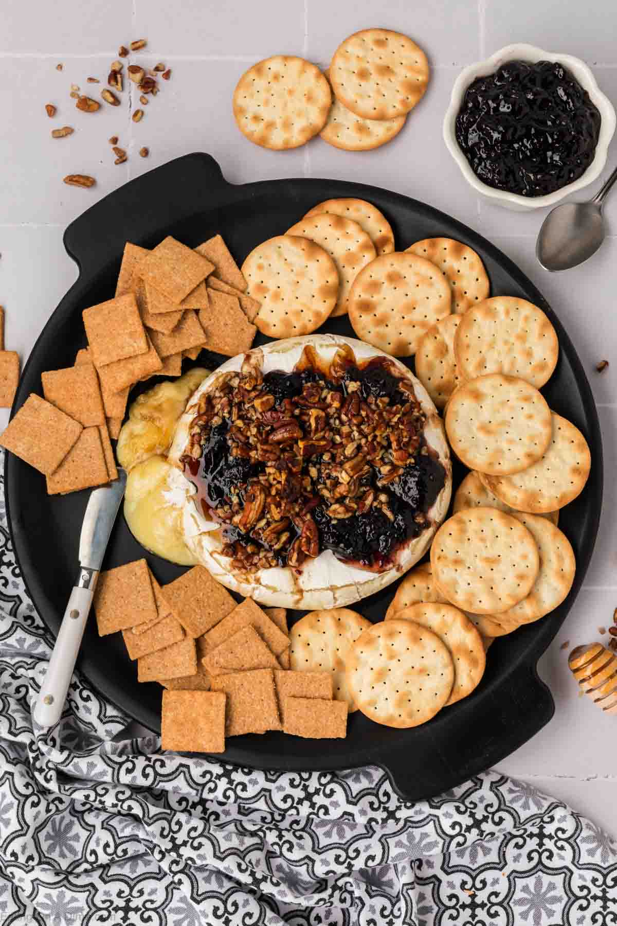 Baked Brie with Jelly on a platter with a assortment of crackers