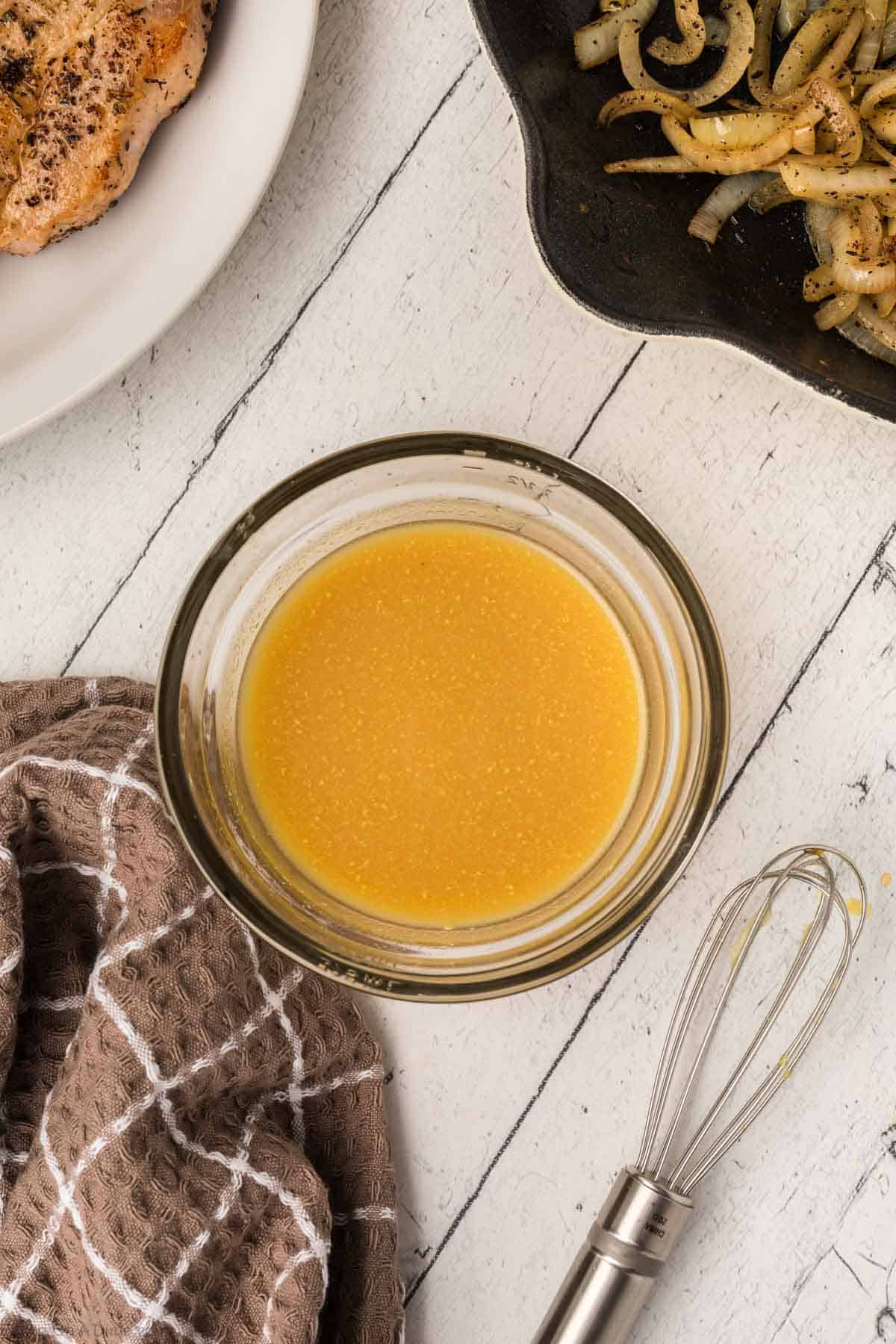 Combining chicken broth, mustard, and honey in a bowl