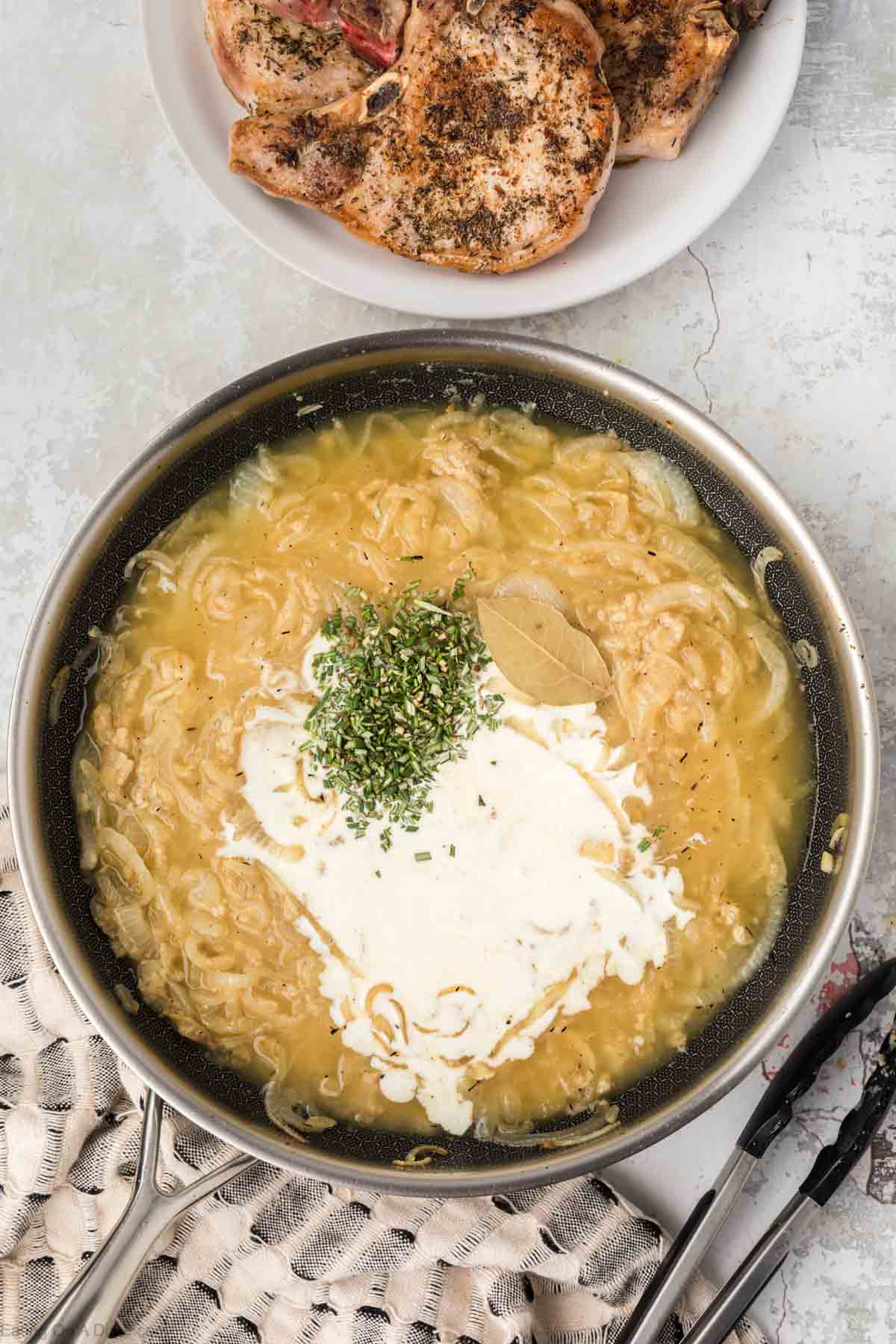 Heavy cream poured into broth in skillet with cooked onions