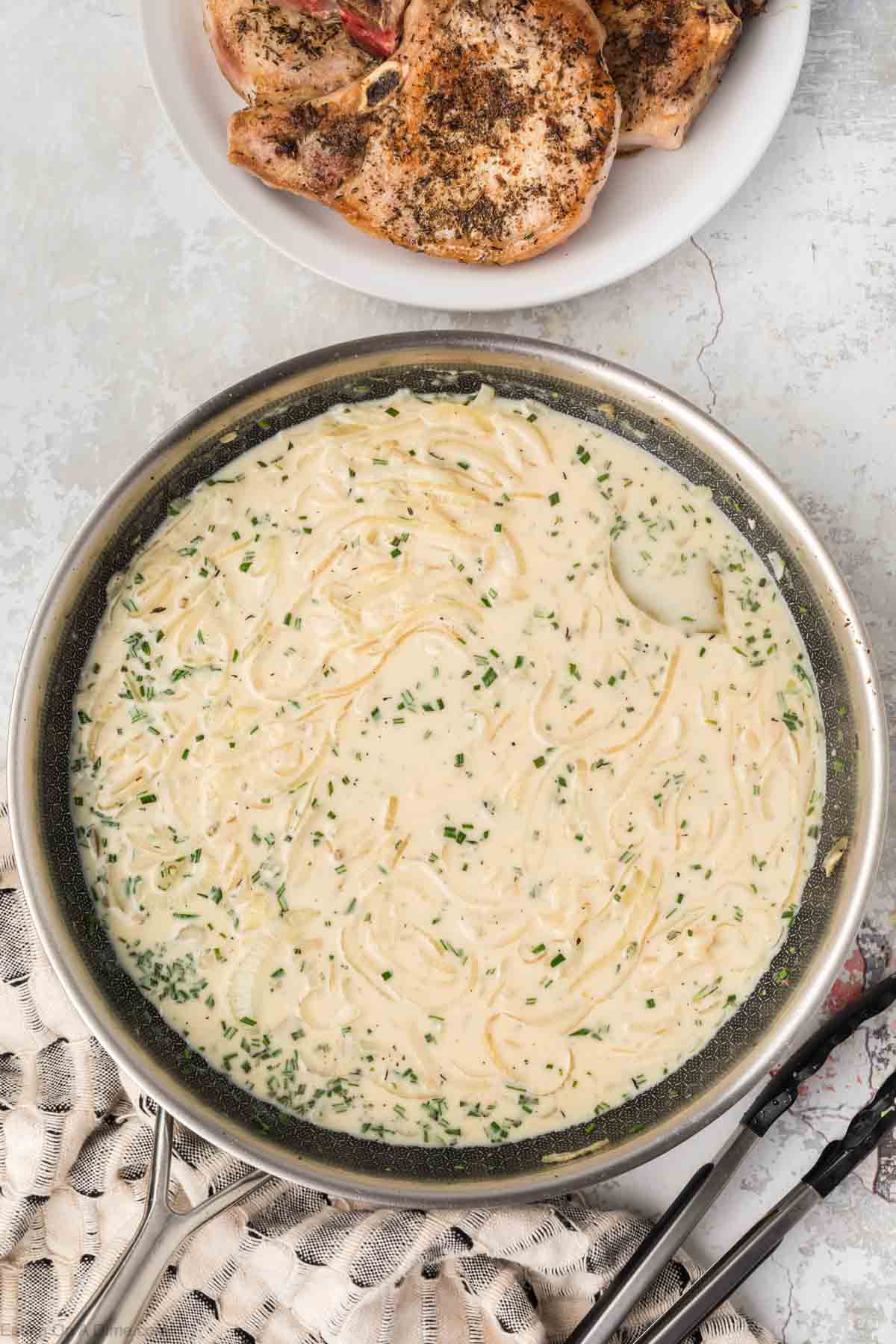 Creamy sauce in skillet poured over onions