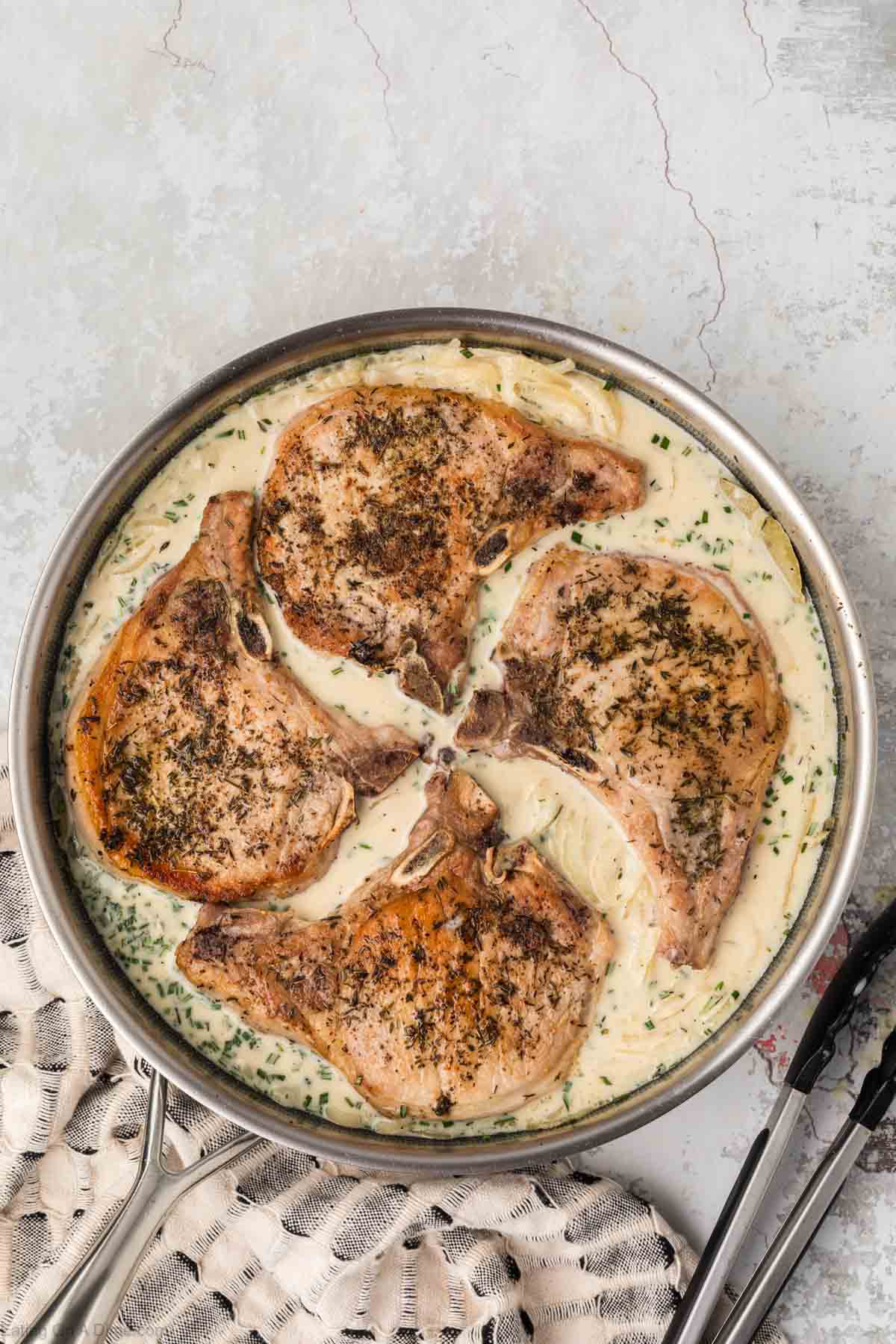 Golden Brown pork chops placed in skillet with gravy