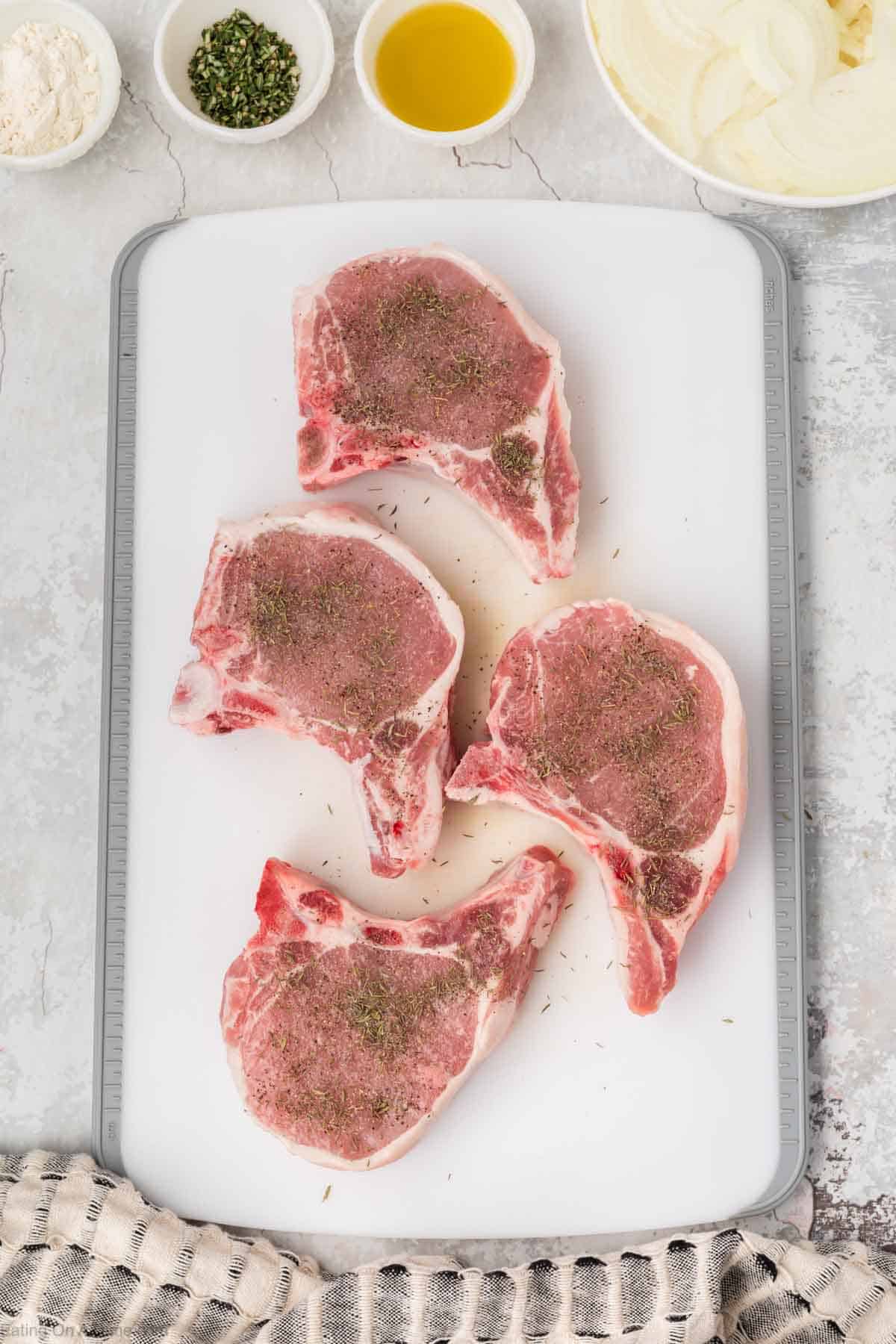 Seasoned pork chops on a cutting board