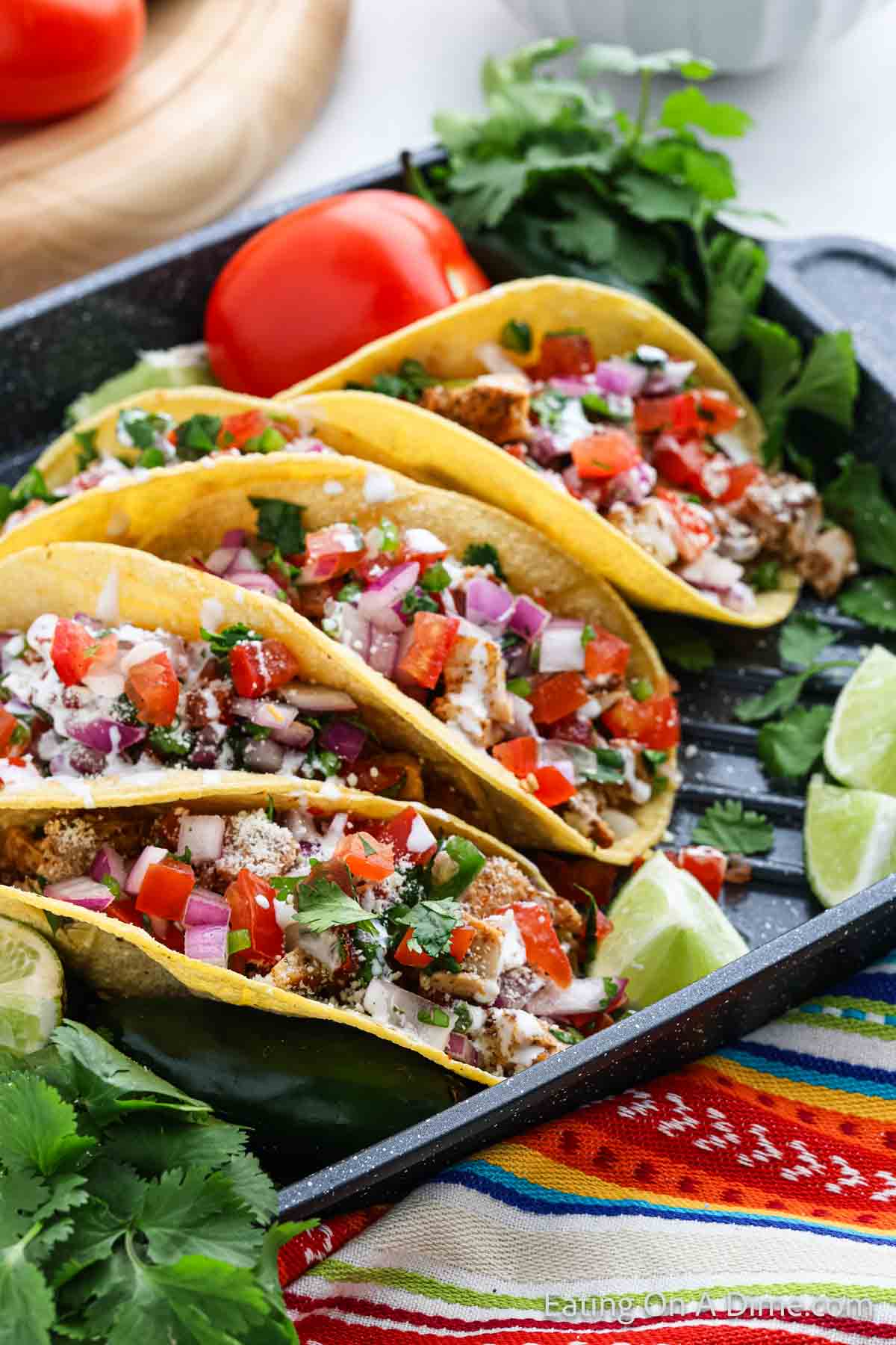 Chicken Street Tacos topped with diced tomatoes in corn tortillas on a platter