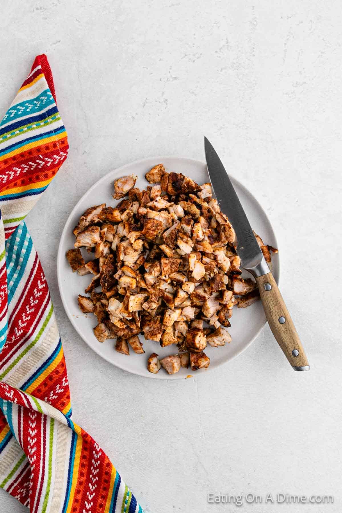 Diced cooked chicken on a plate with a knife