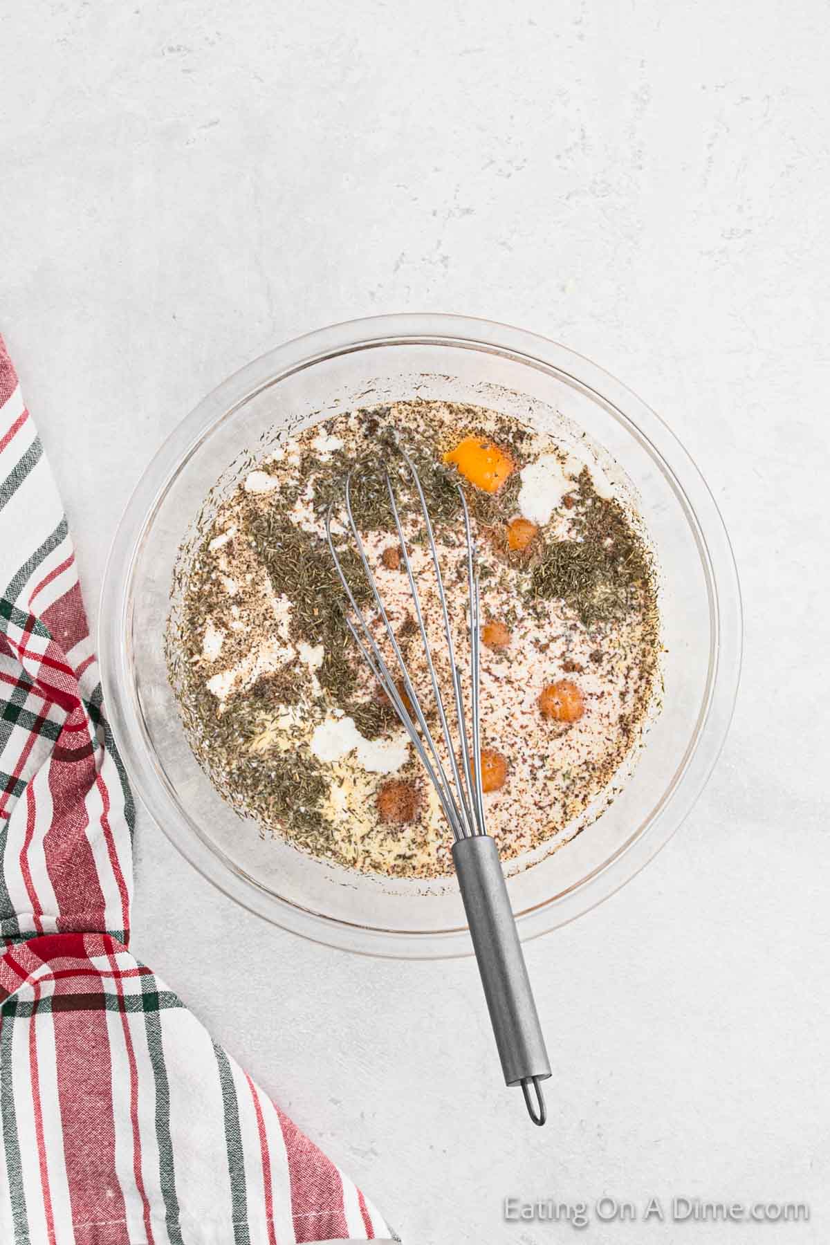 Eggs mixed with milk and spices in a bowl with a whisk