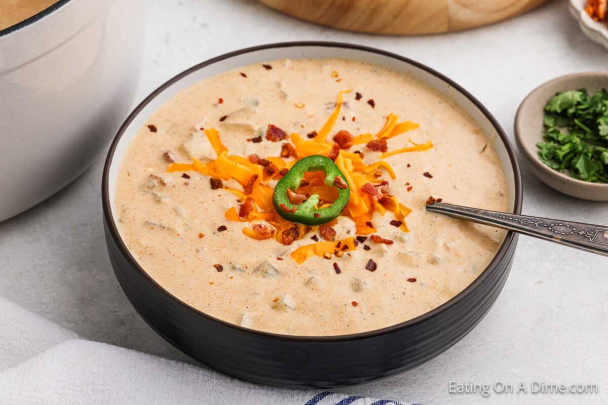 Bowl of Jalapeno Popper Soup topped with cheddar cheese, chopped bacon and slice jalapeno