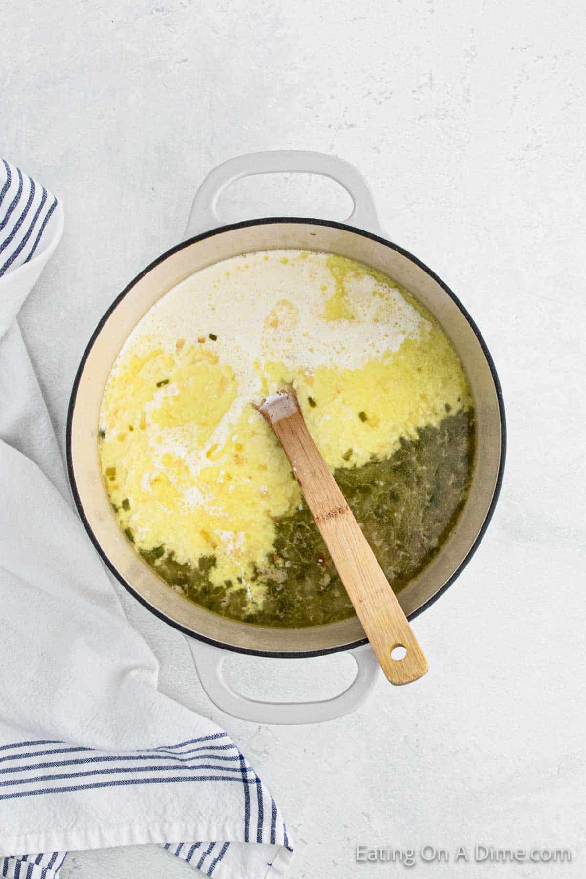 Stirring in heavy cream with a wooden spoon in a large pot