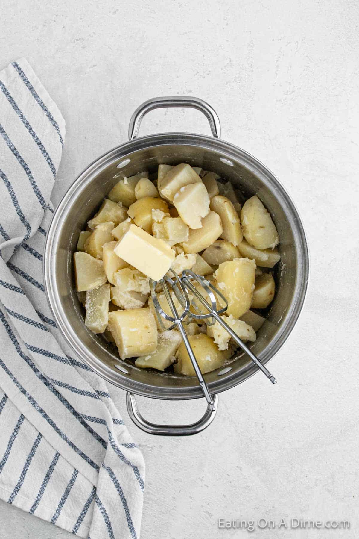 Cooked potatoes in a large pot topped with butter