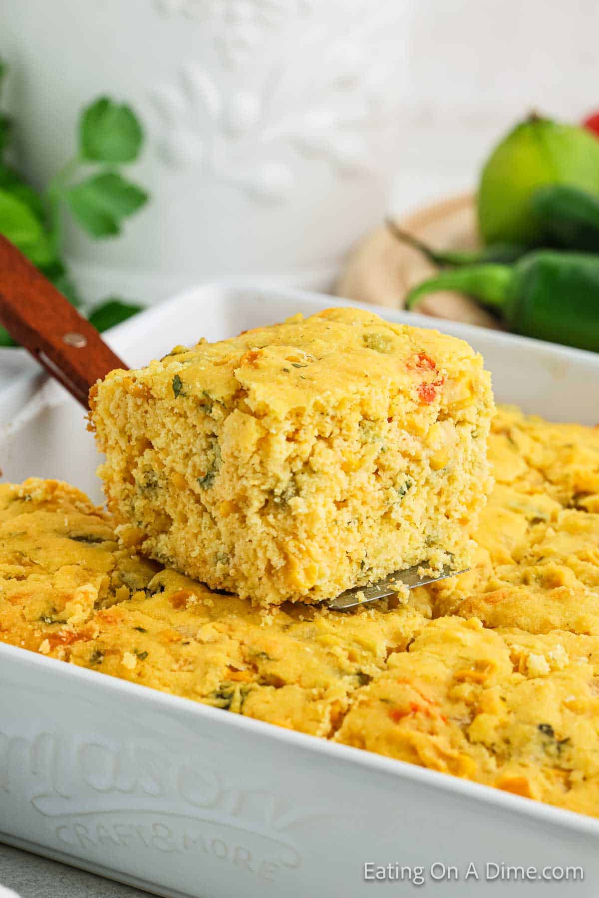 Baked Mexican Cornbread cut into squares with a slice placed on top of the cornbread