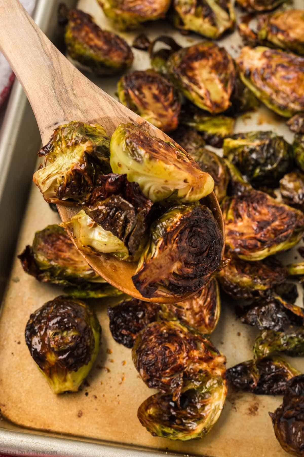 Roasted Brussel Sprouts on a baking sheet with a wooden spoons