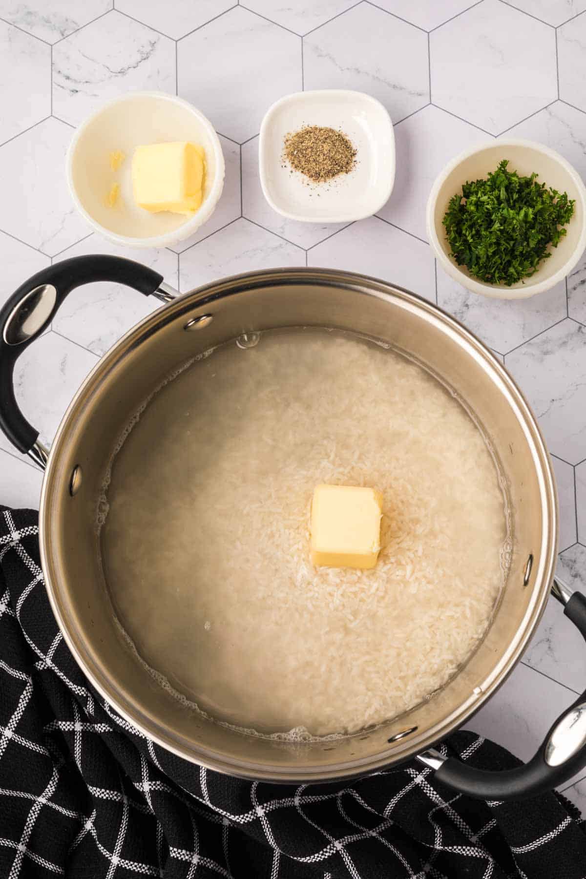 Large pot with rice, water and butter with small bowls of pepper, parsley, and butter