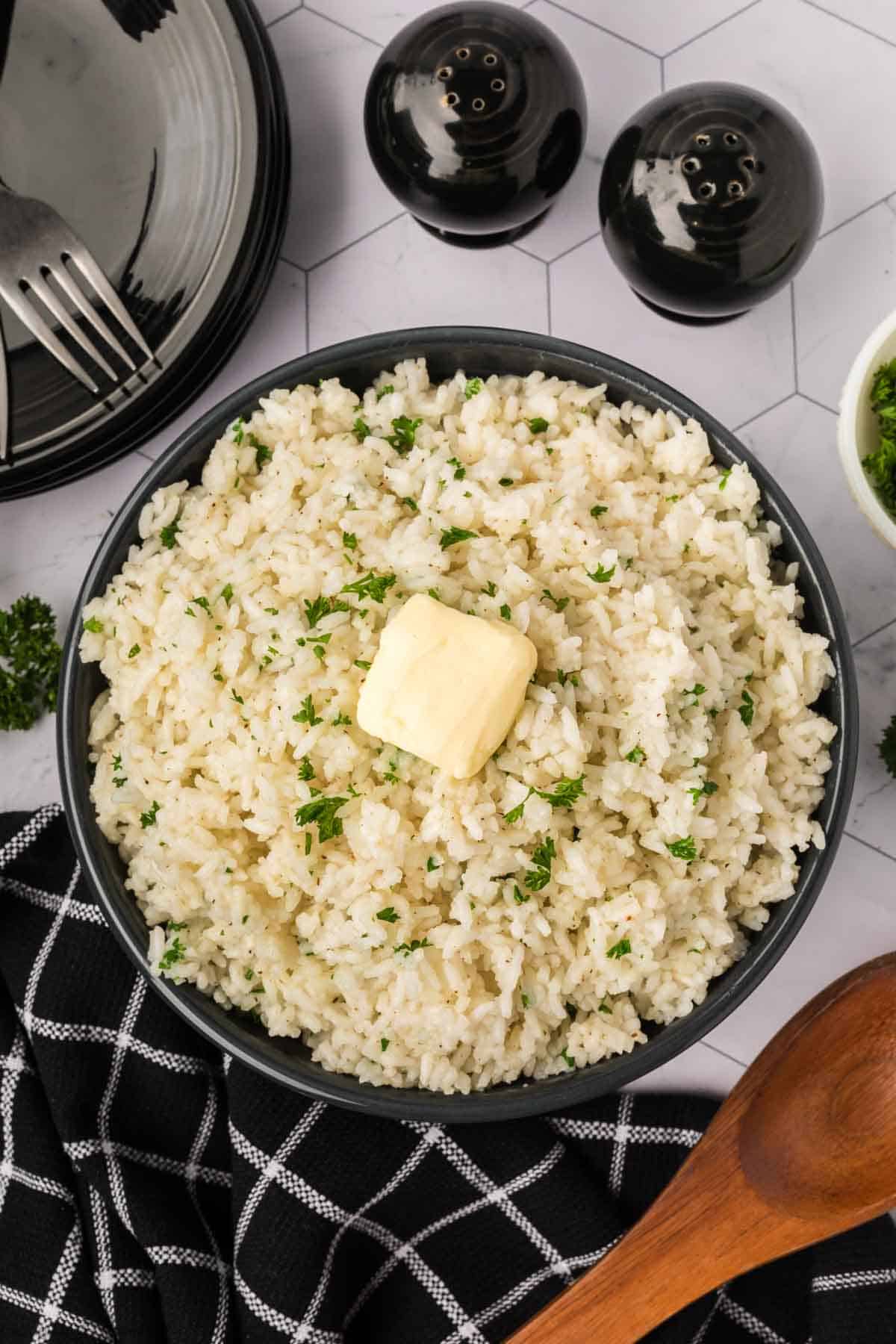 White rice garnished with fresh parsley and butter in a bowl