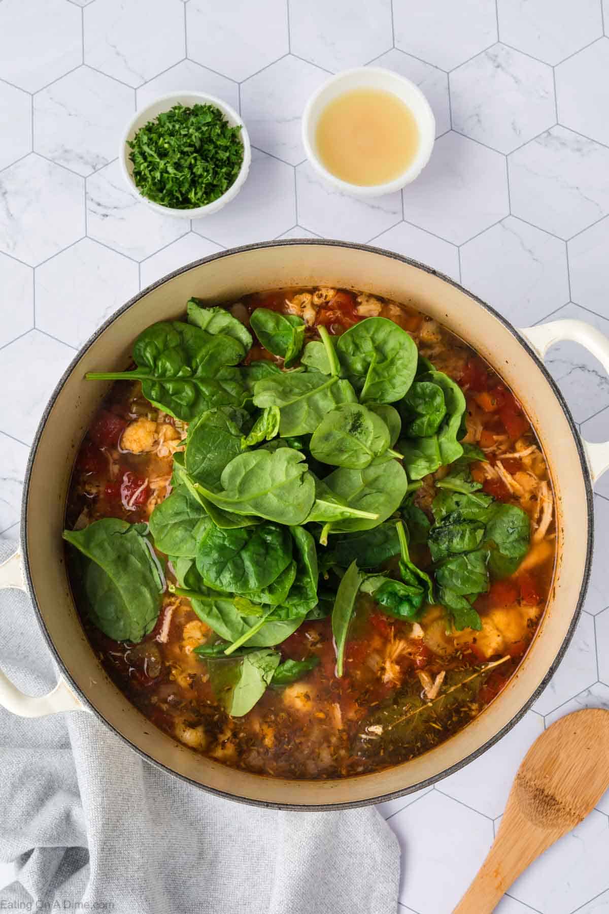 Fresh spinach added to the large pot with the broth and other turkey soup ingredients