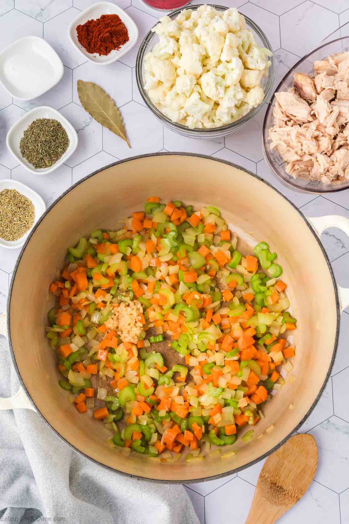 Cooked chopped celery, carrots, and onions in a large pot topped with minced garlic