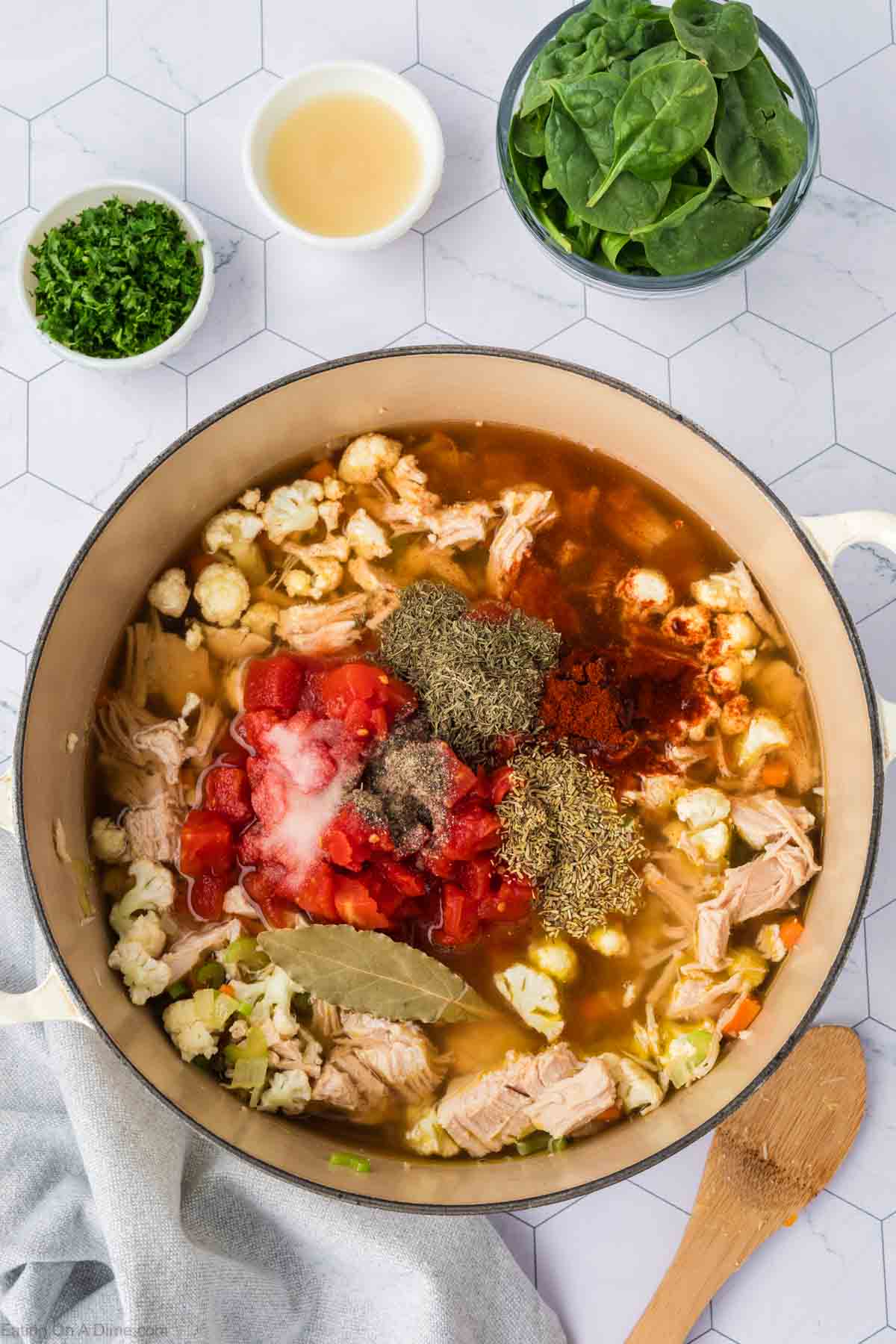 Broth poured into the pot with chopped cauliflower and turkey topped with seasoning and diced tomatoes