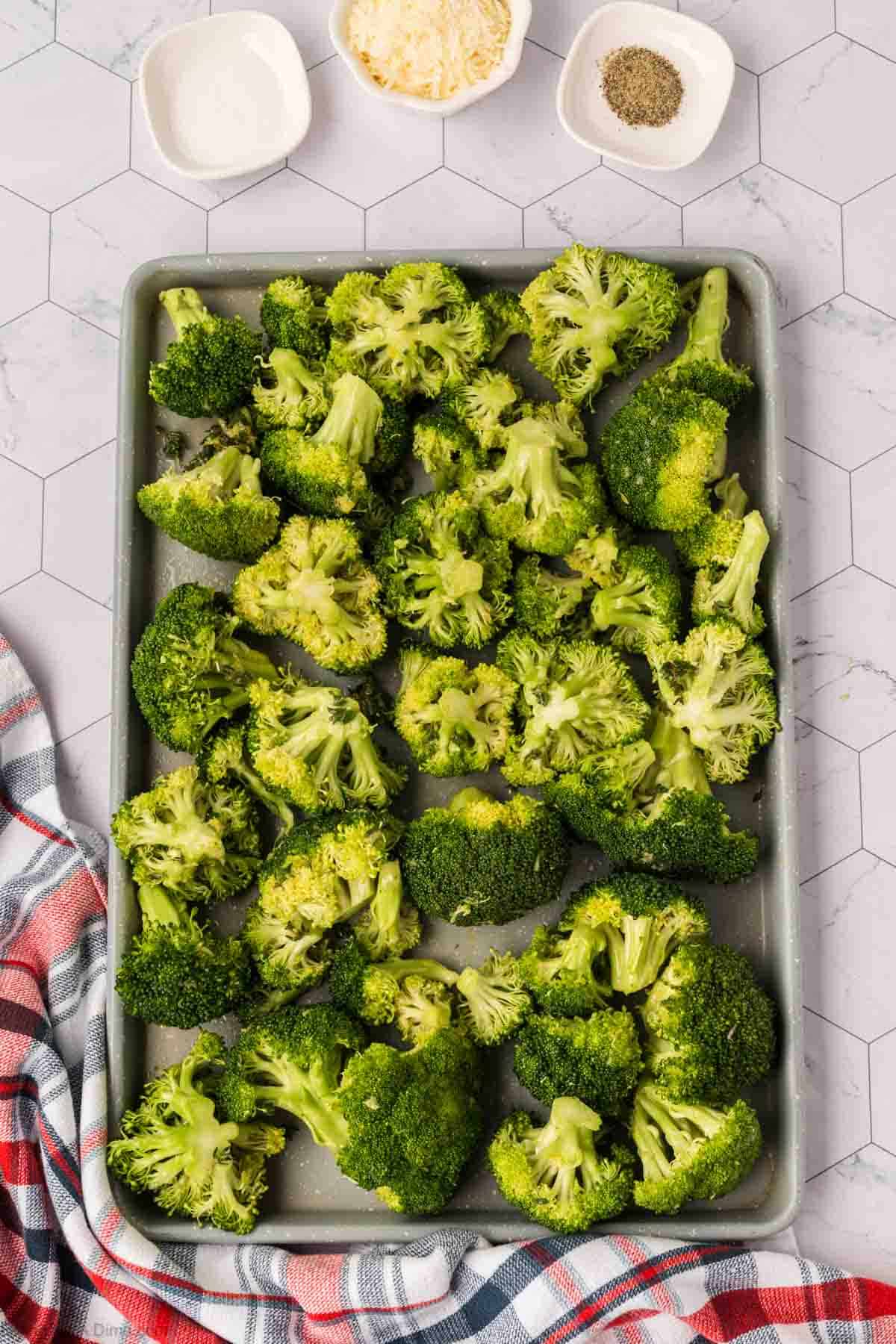 Broccoli Florets on a baking sheet with small bowls of spices