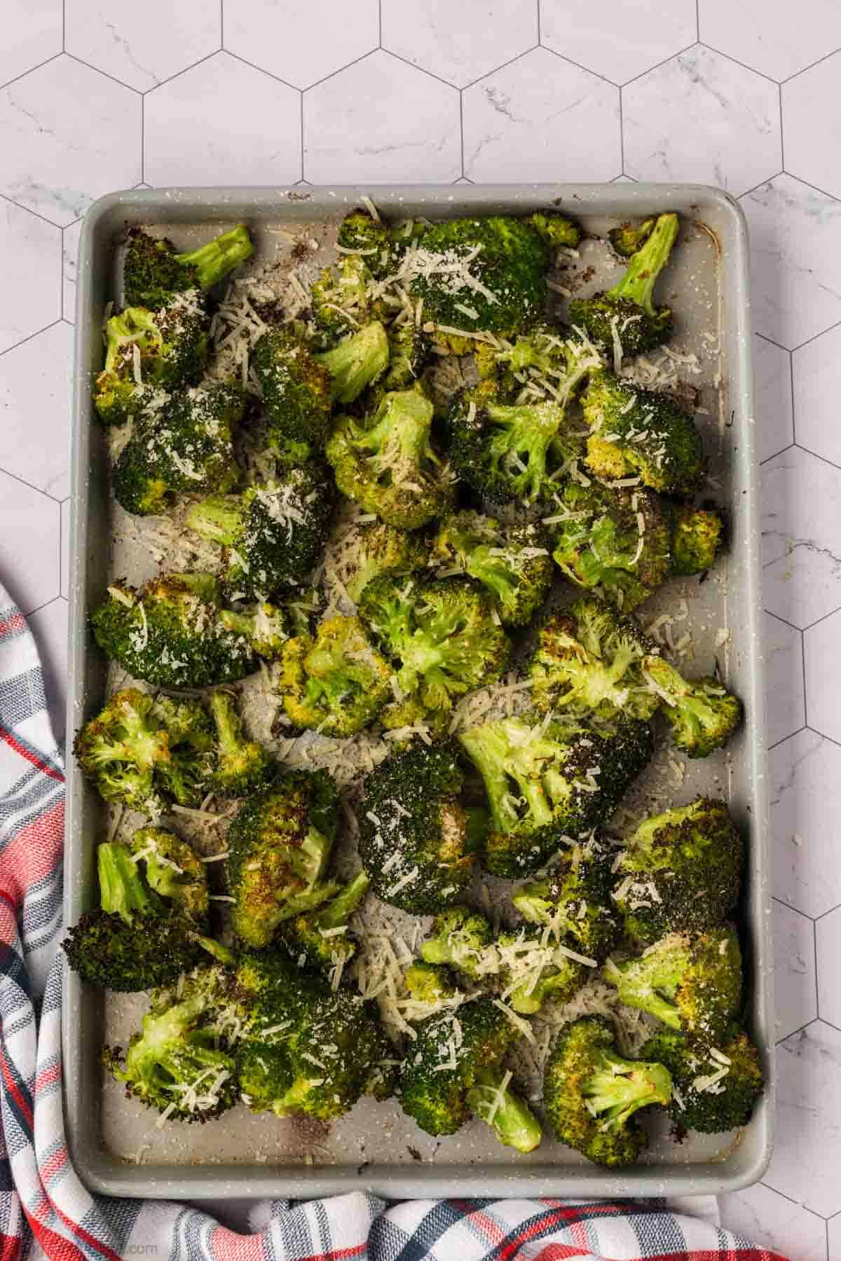 Roasted Broccoli on a baking sheet topped with shredded parmesan cheese