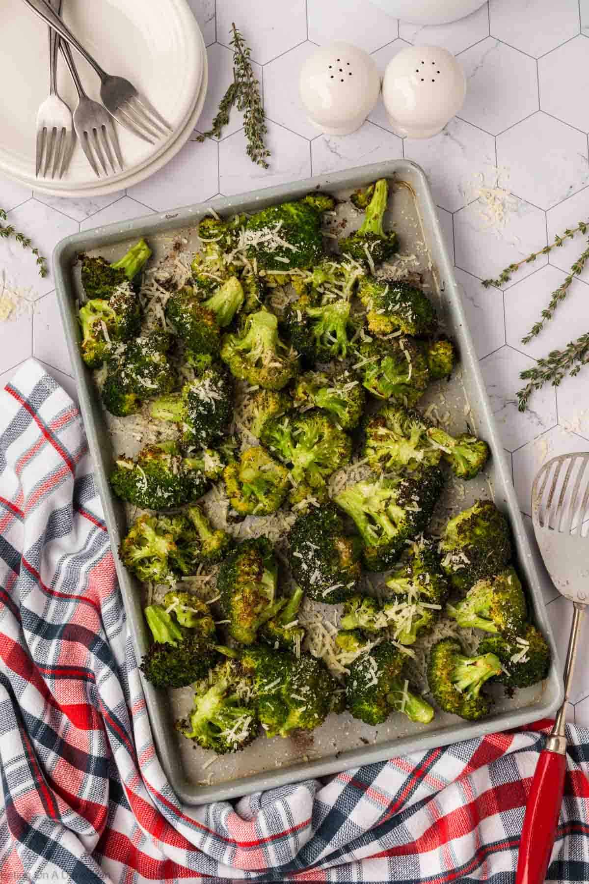 Roasted Broccoli topped with shredded parmesan cheese on a baking sheet