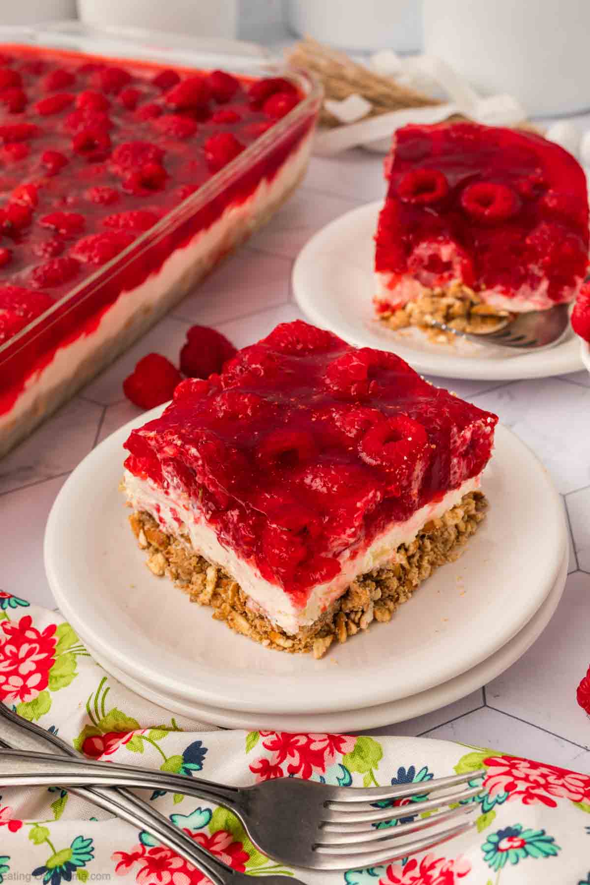 Slice of Raspberry Jello Salad on plate with Raspberry Jello Salad in a  baking dish on the side