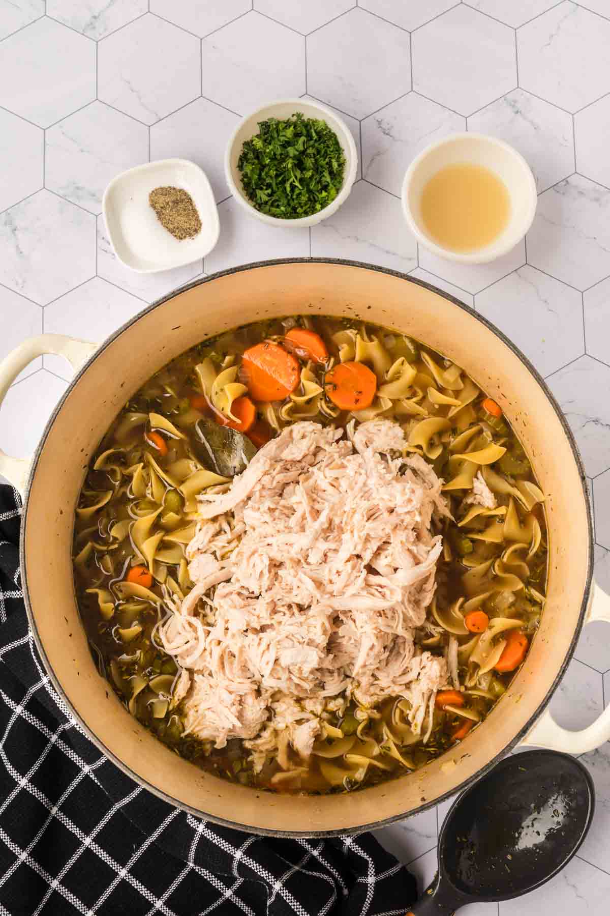 Shredded turkey topped on the egg noodles, broth and slice carrots in the large pot