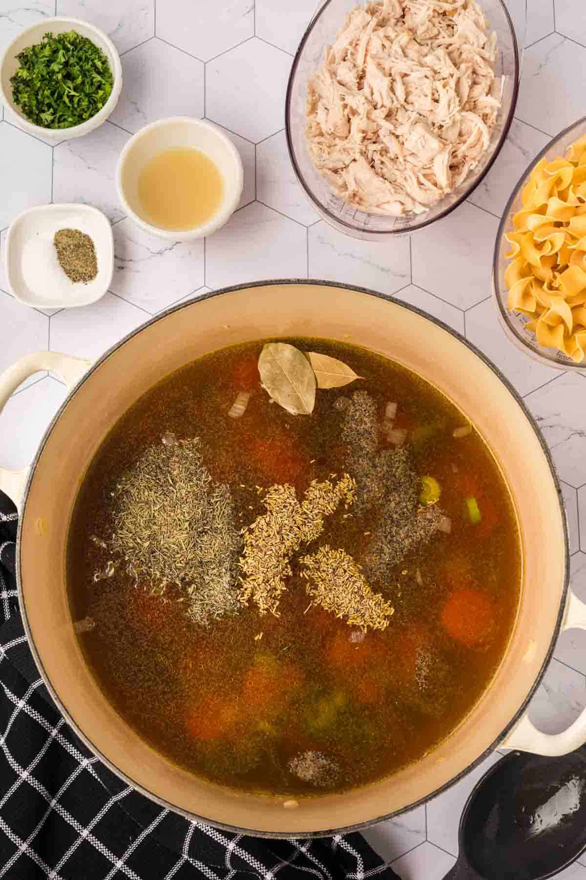 Broth covering the chopped vegetables in a large pot and topped with the spices