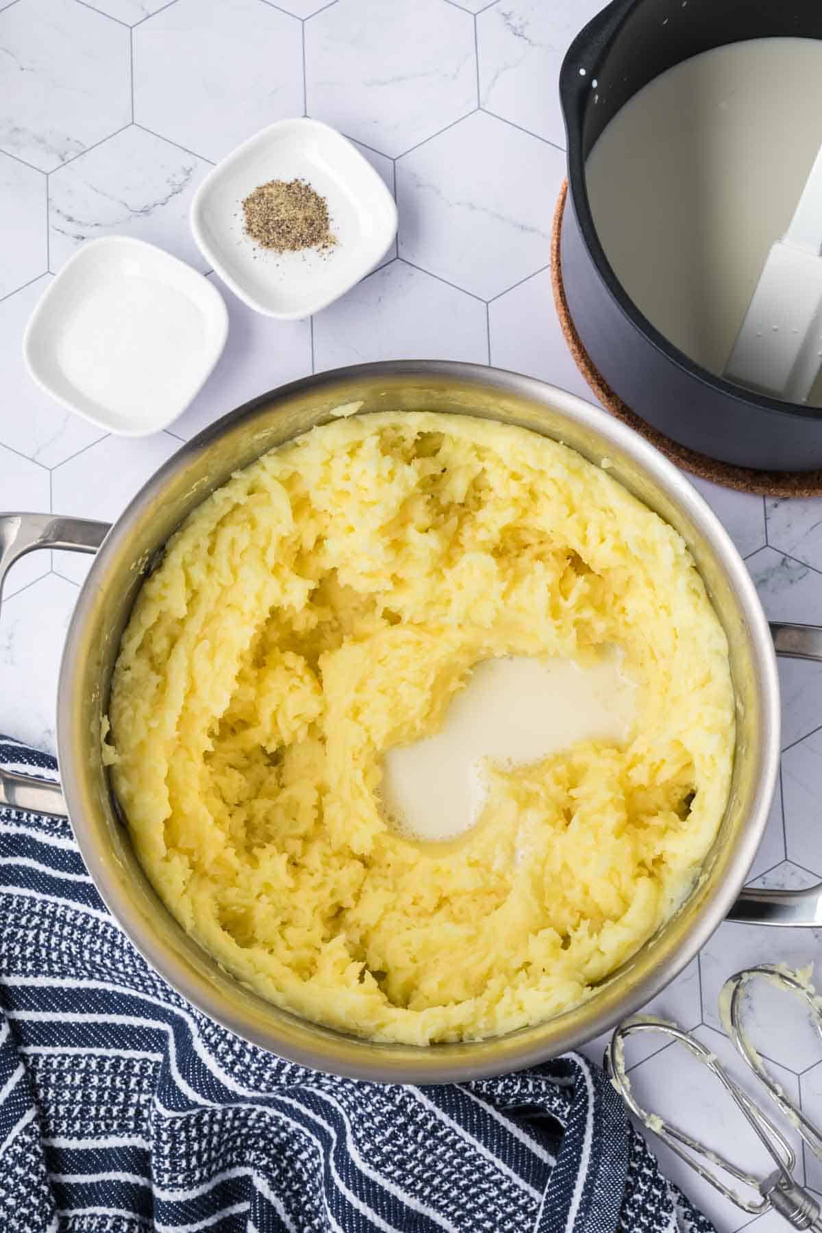 Mashed Yukon Gold Potatoes in a large pot topped with the milk mixture