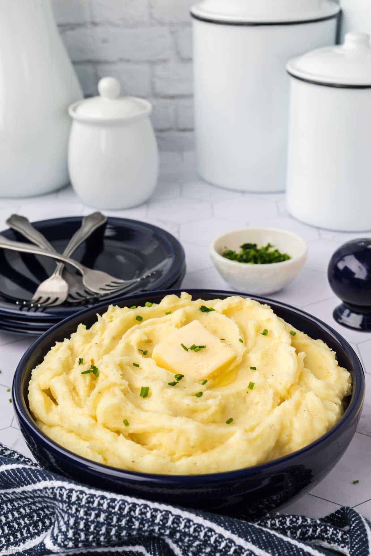 Yukon Gold Mashed Potatoes in a bowl topped with butter and chives