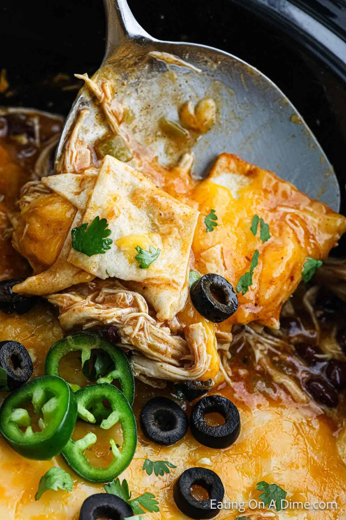 Chicken enchiladas in the slow cooker with a serving on a spatula