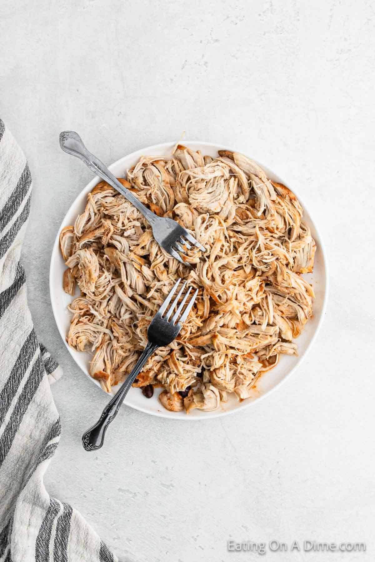 Shredded chicken on a plate with two forks