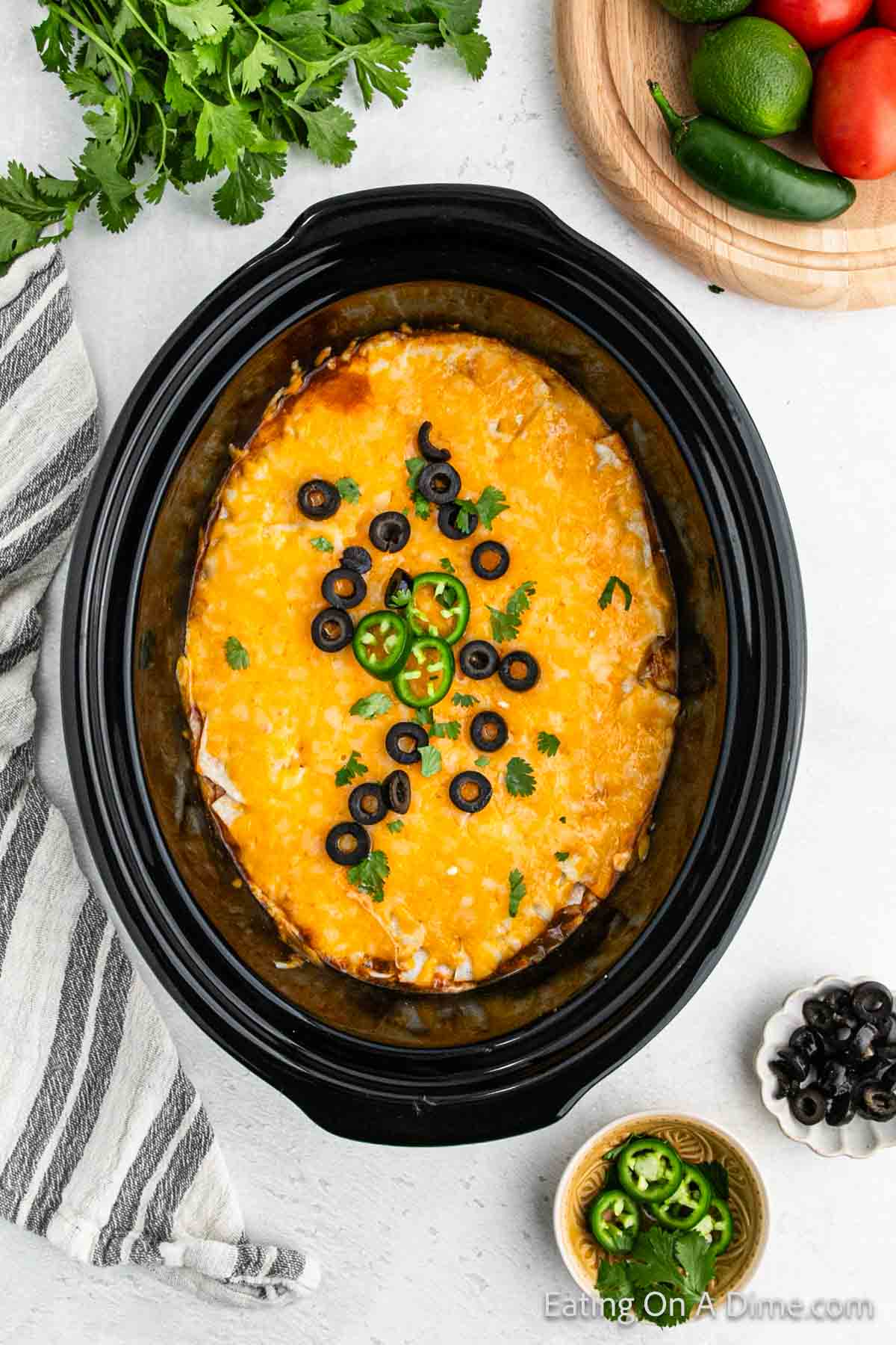 Chicken Enchiladas in the slow cooker topped with melted cheese, slice black olives and jalapenos