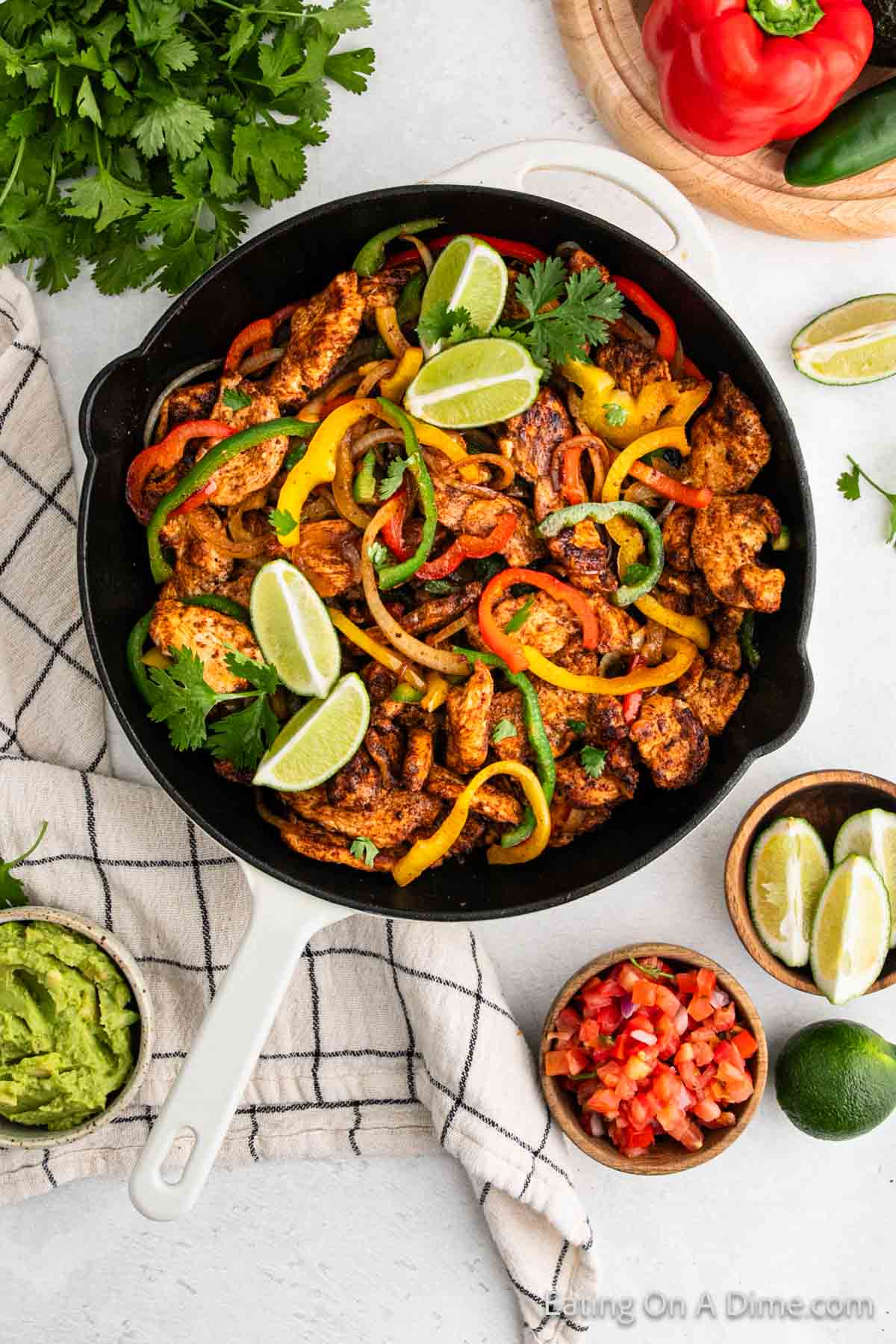 Chicken Fajita Meat in a cast iron skillet with yellow, green red peppers topped with fresh lime wedges