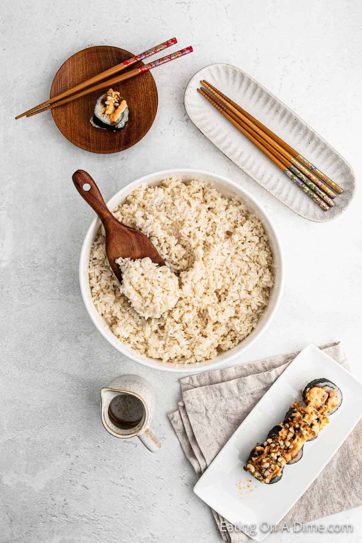 Sushi Rice in a large bowl with a wooden spoon with chopsticks on the side